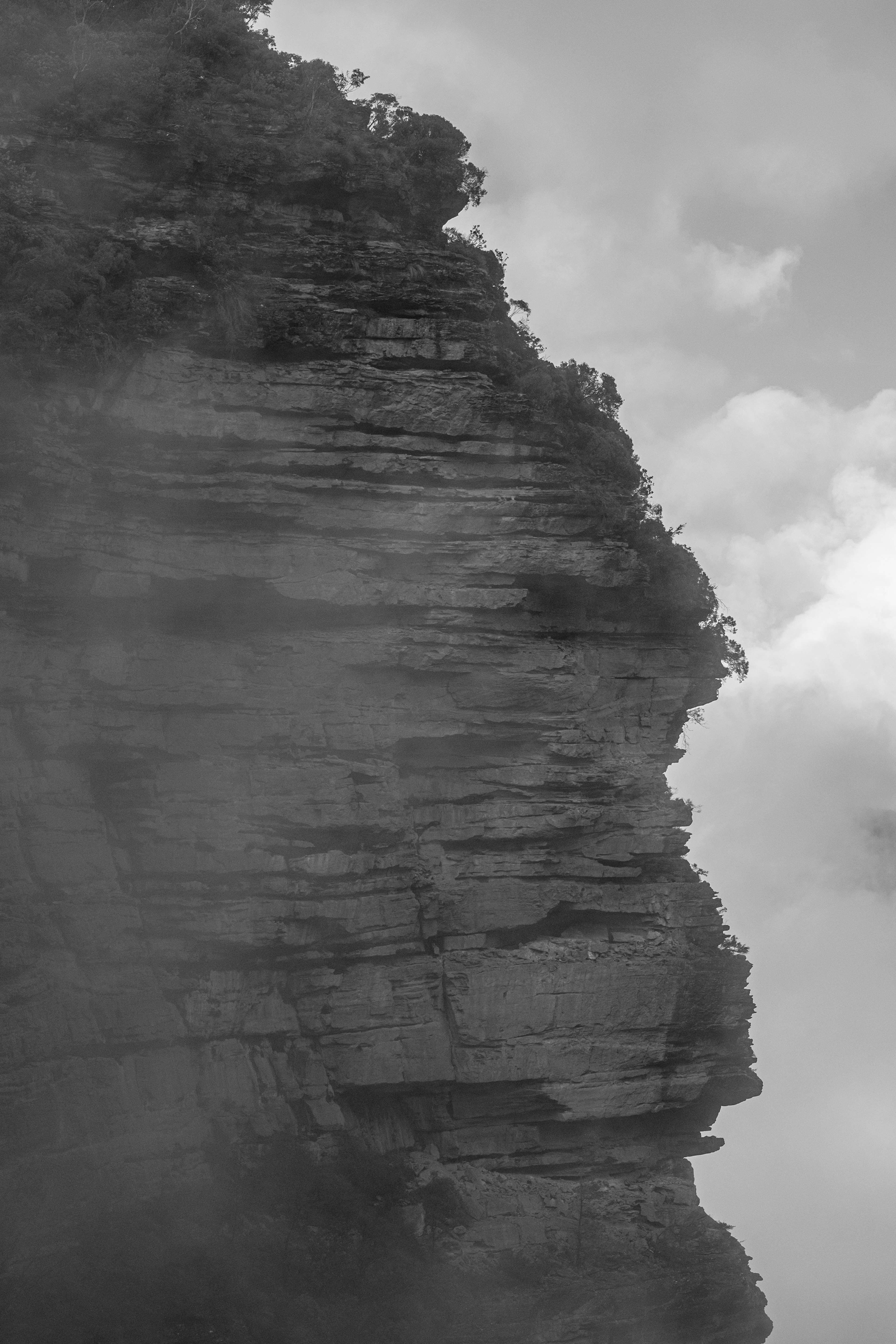 Paysage en noir et blanc avec une falaise escarpée au milieu des nuages