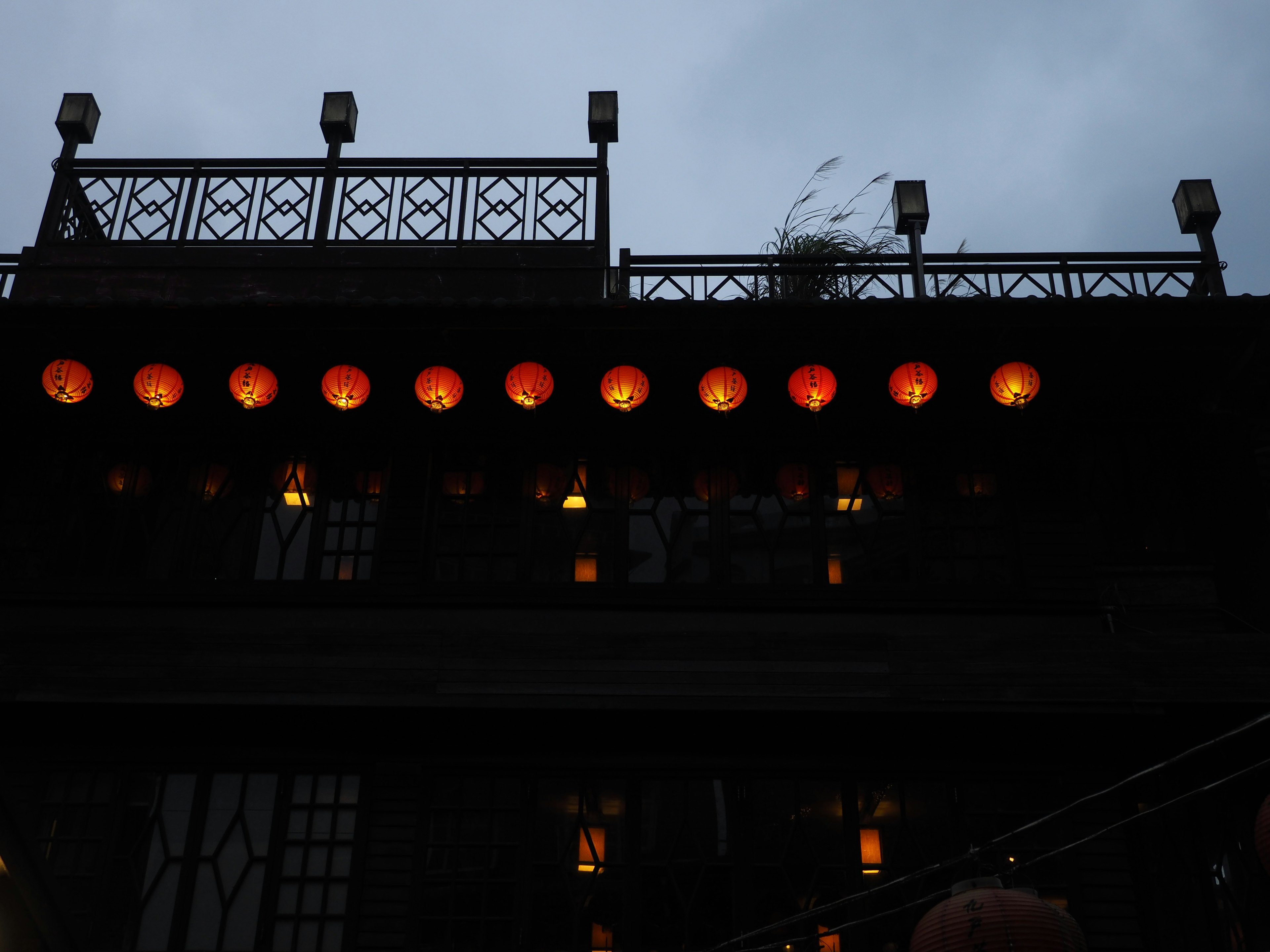 Exterior de un edificio decorado con faroles brillantes contra un cielo crepuscular