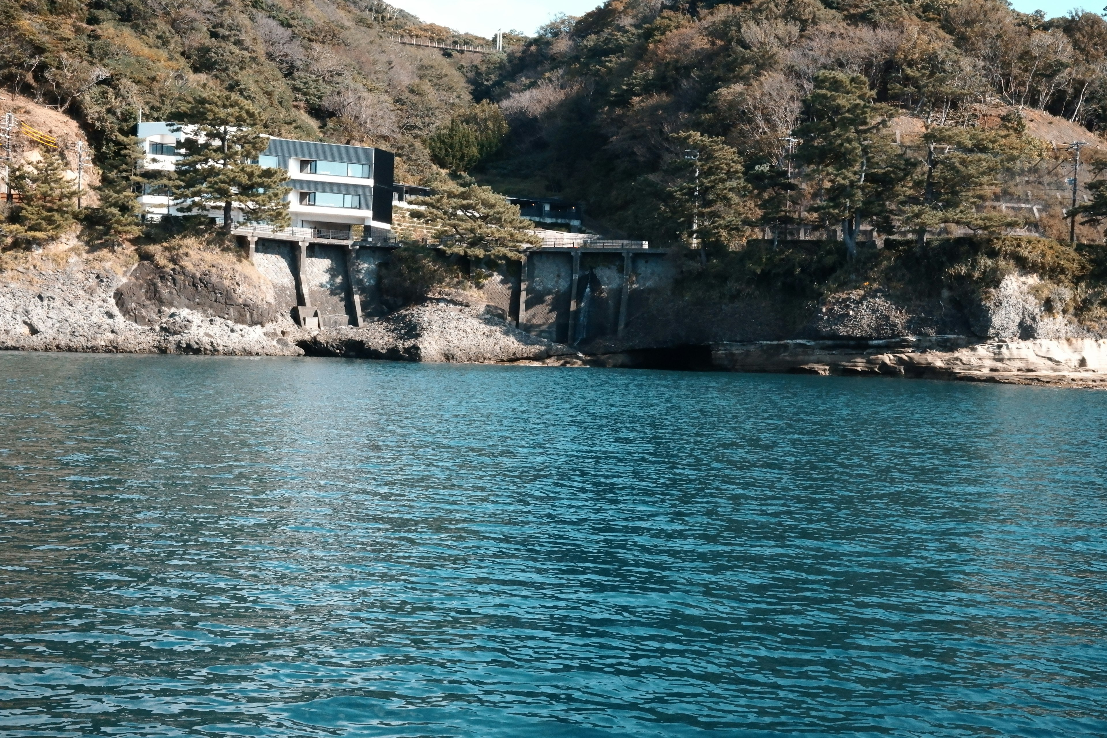 Edificio moderno vicino all'acqua blu e colline lussureggianti