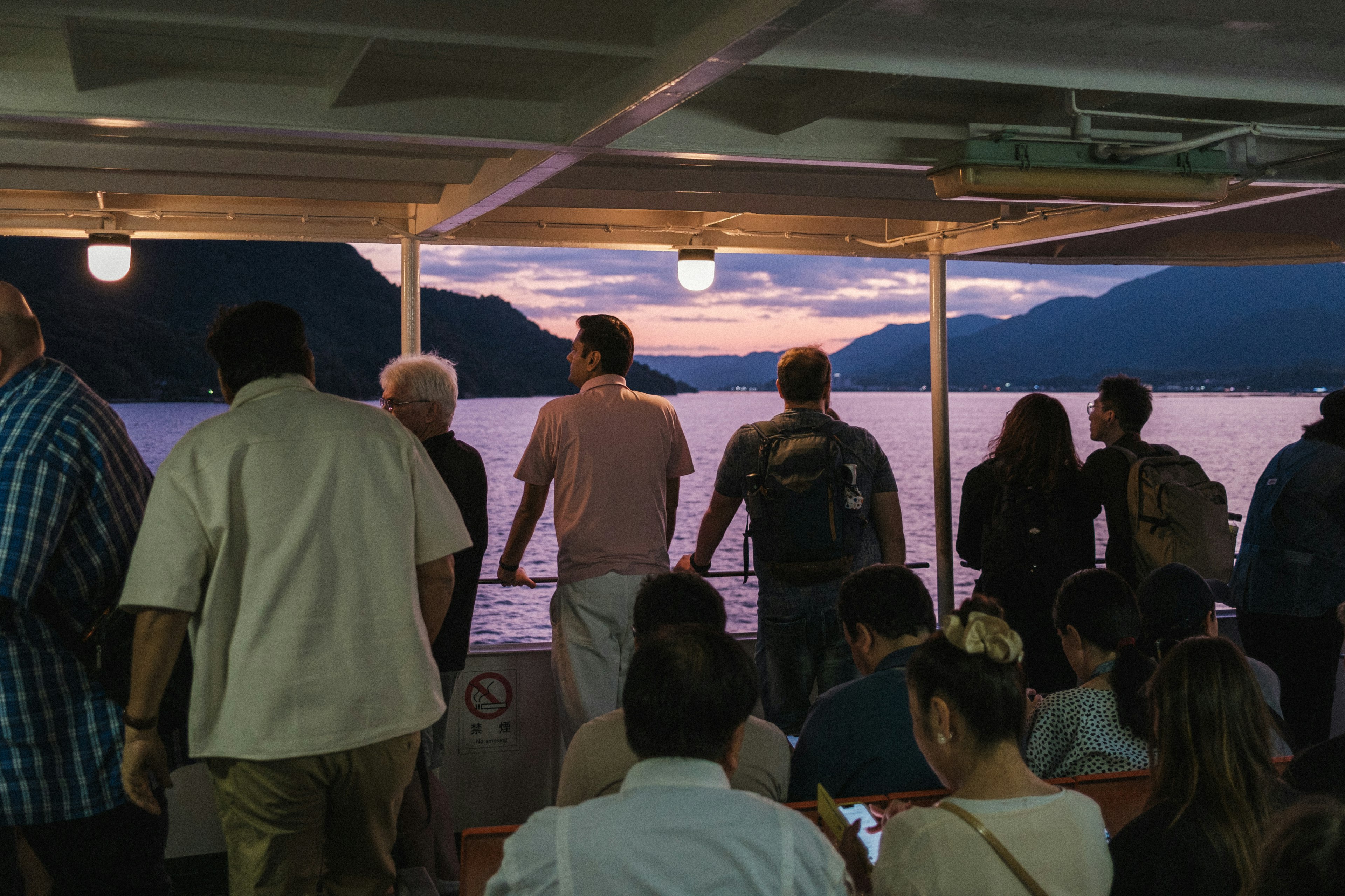 Group of people standing on a boat deck during sunset