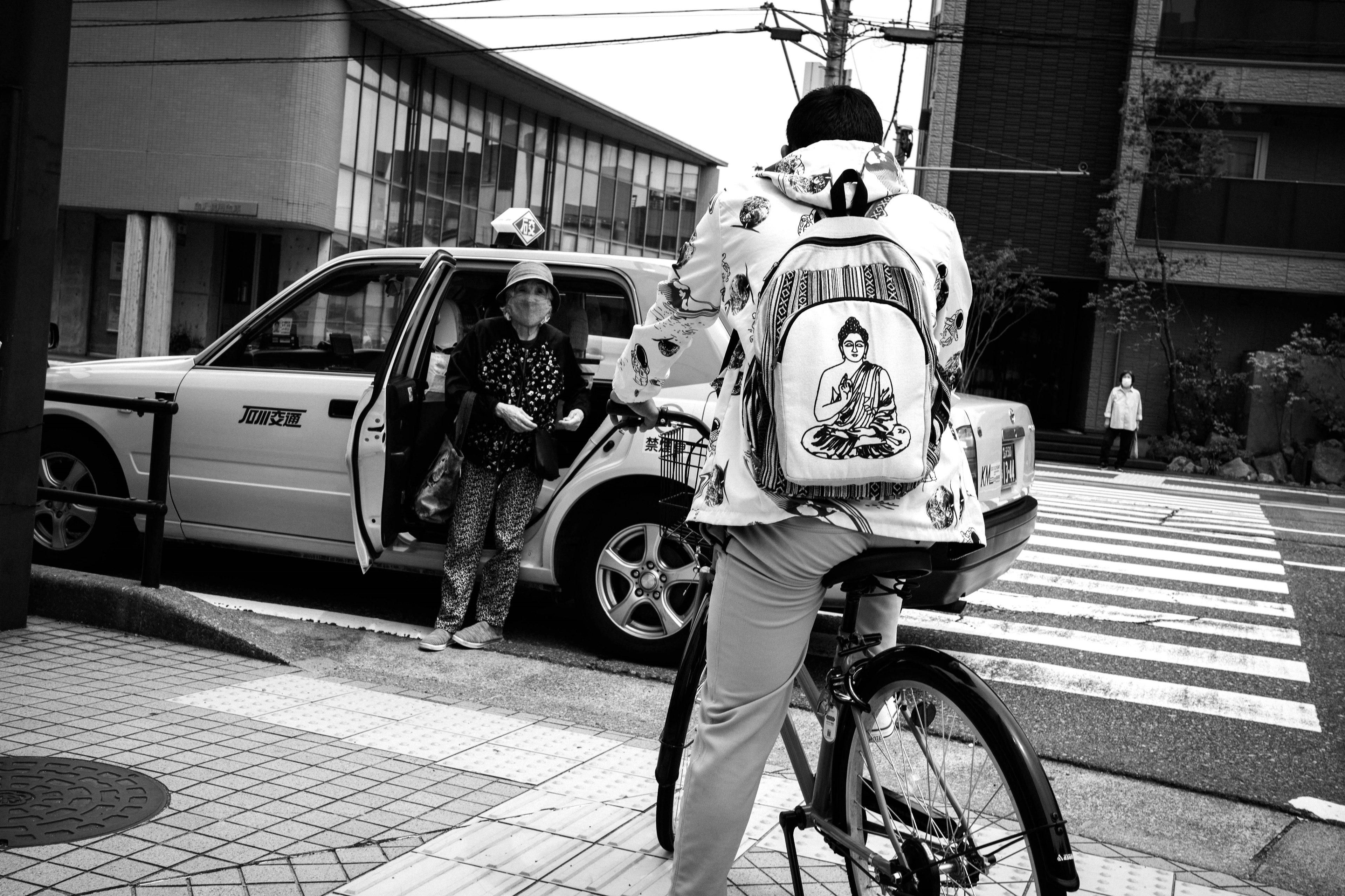 A person on a bicycle waiting near a taxi