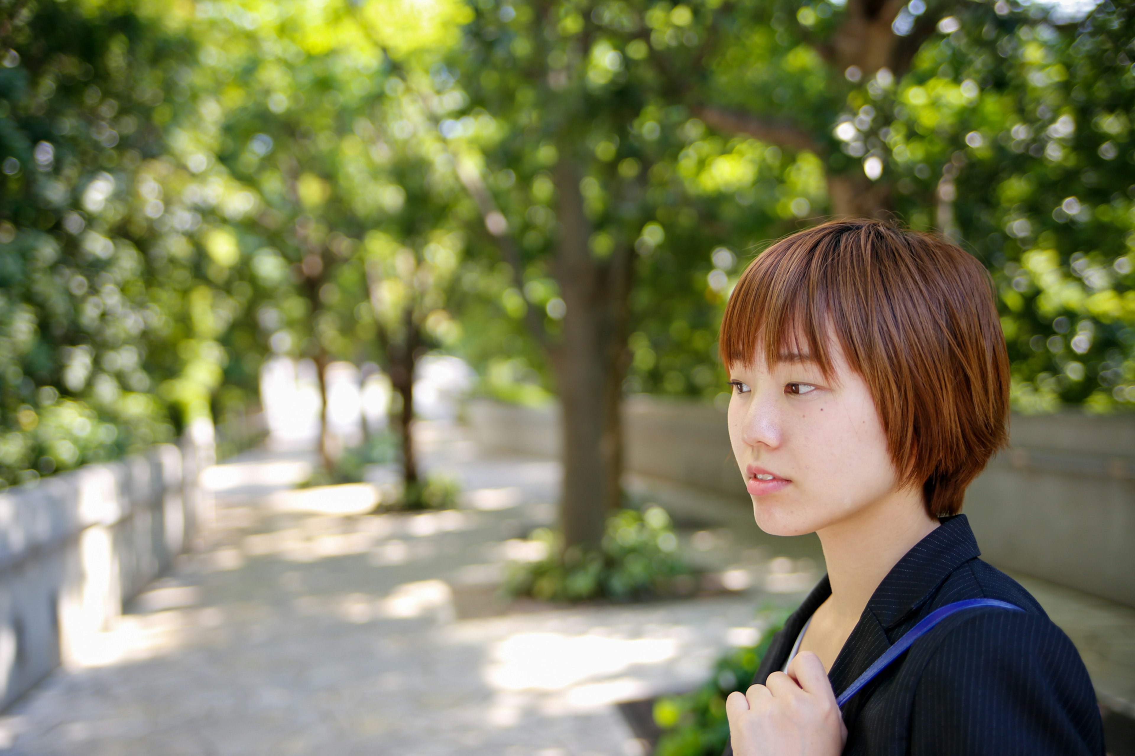 Side profile of a short-haired woman walking among green trees