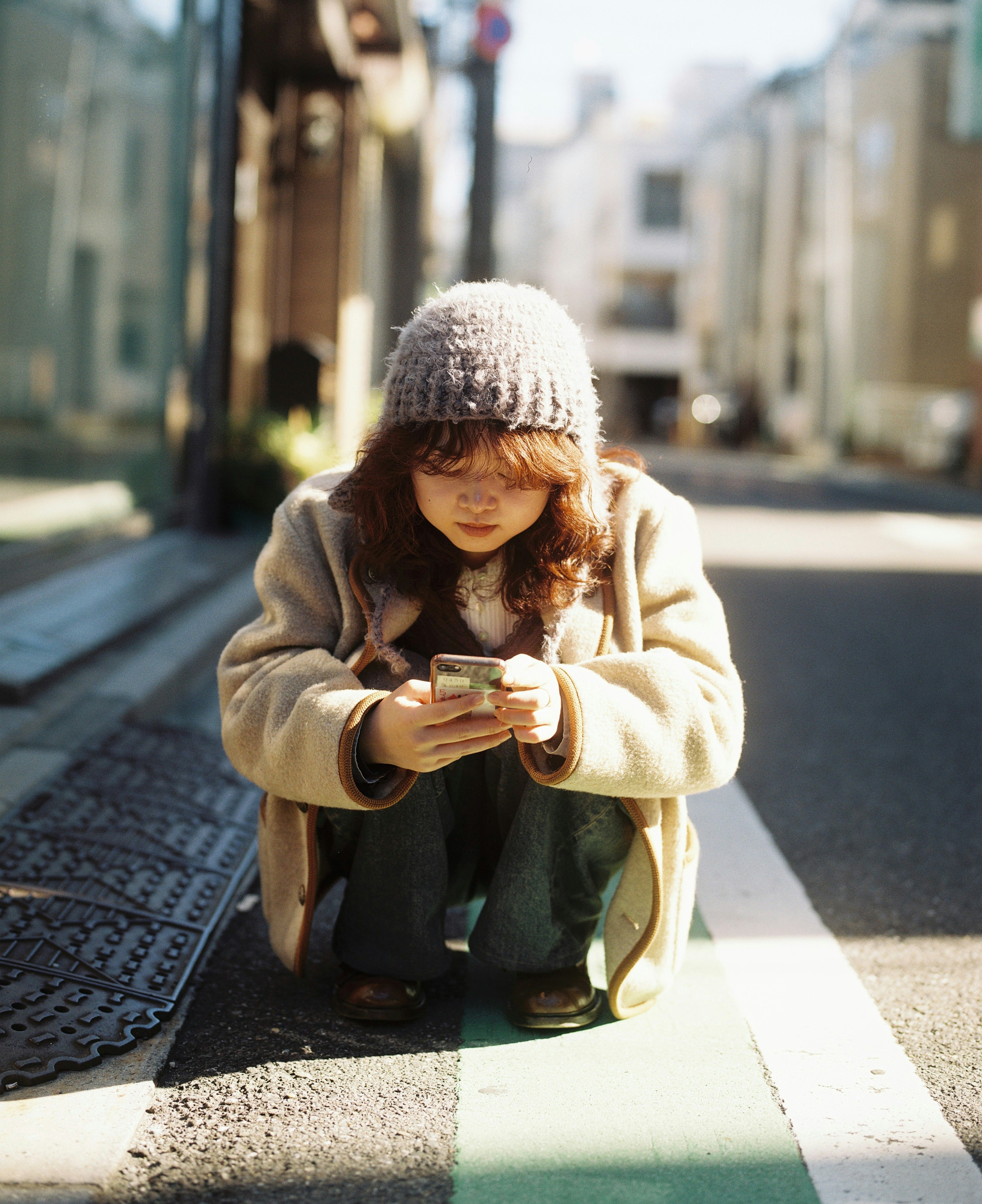 Una donna che usa un telefono cellulare mentre è accovacciata per strada