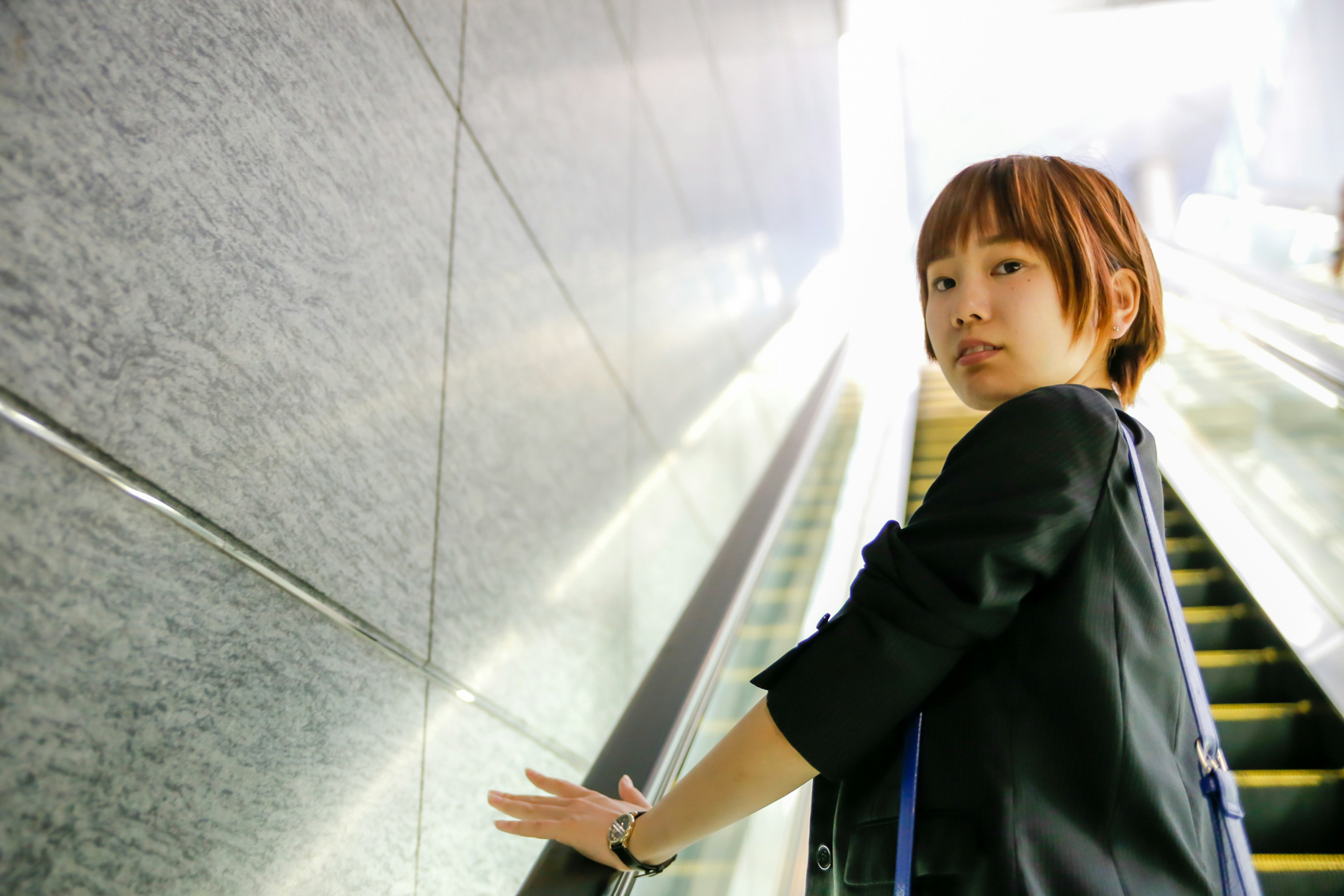 Profile of a woman on an escalator Bright background with nearby wall features