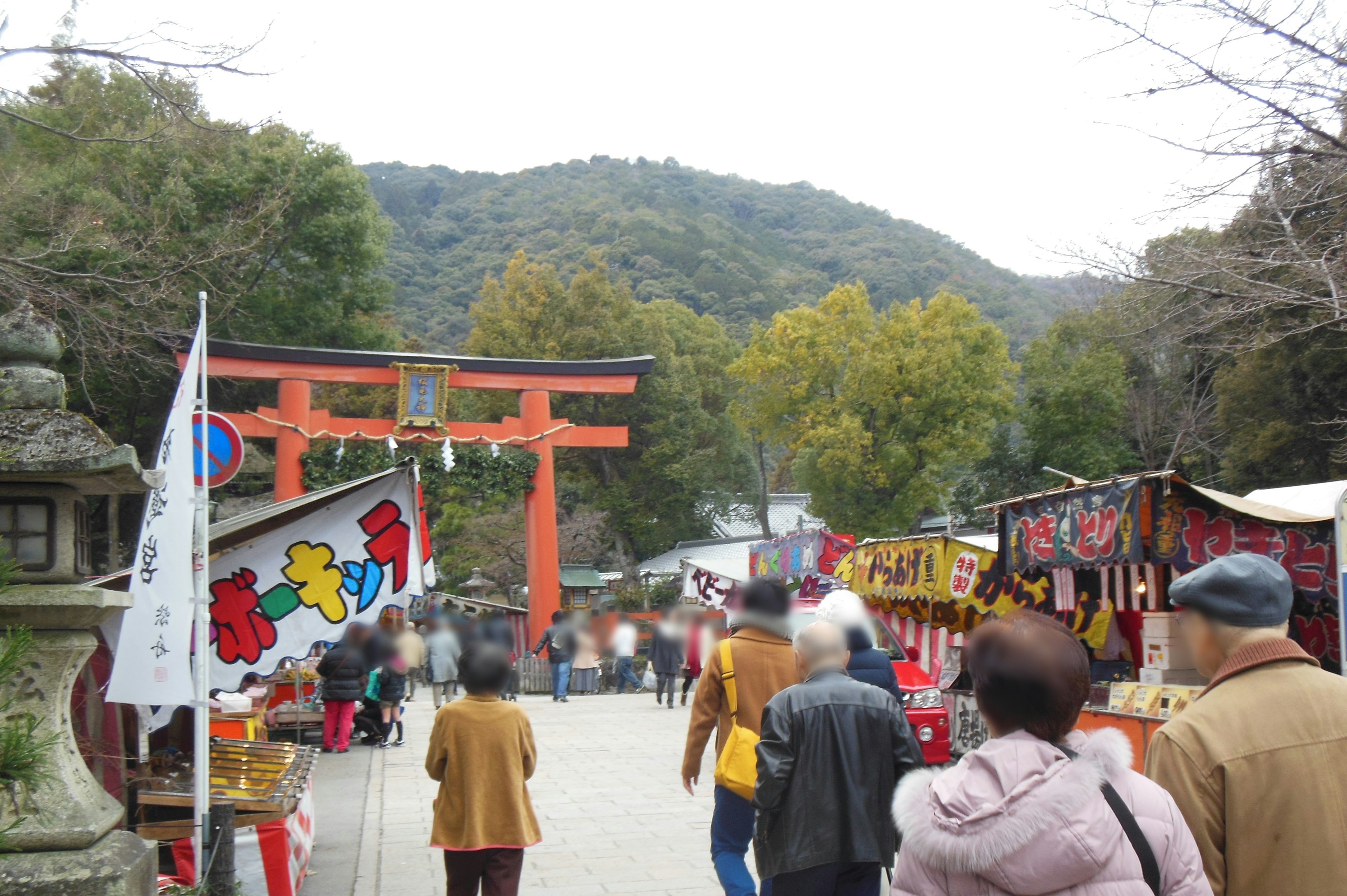 붉은 도리이와 산악 배경이 있는 분주한 시장 거리