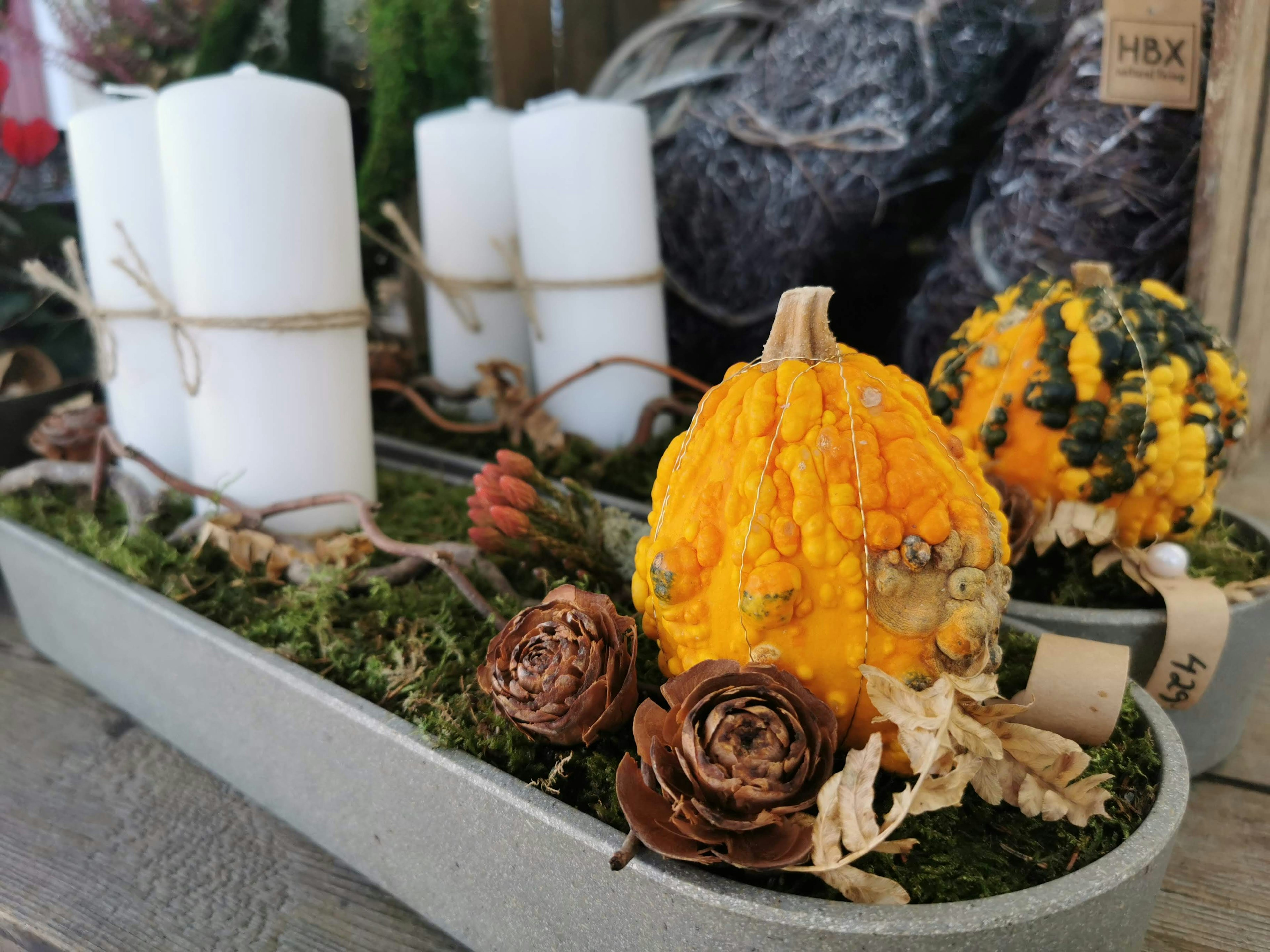 Composizione decorativa con zucca gialla e candele bianche