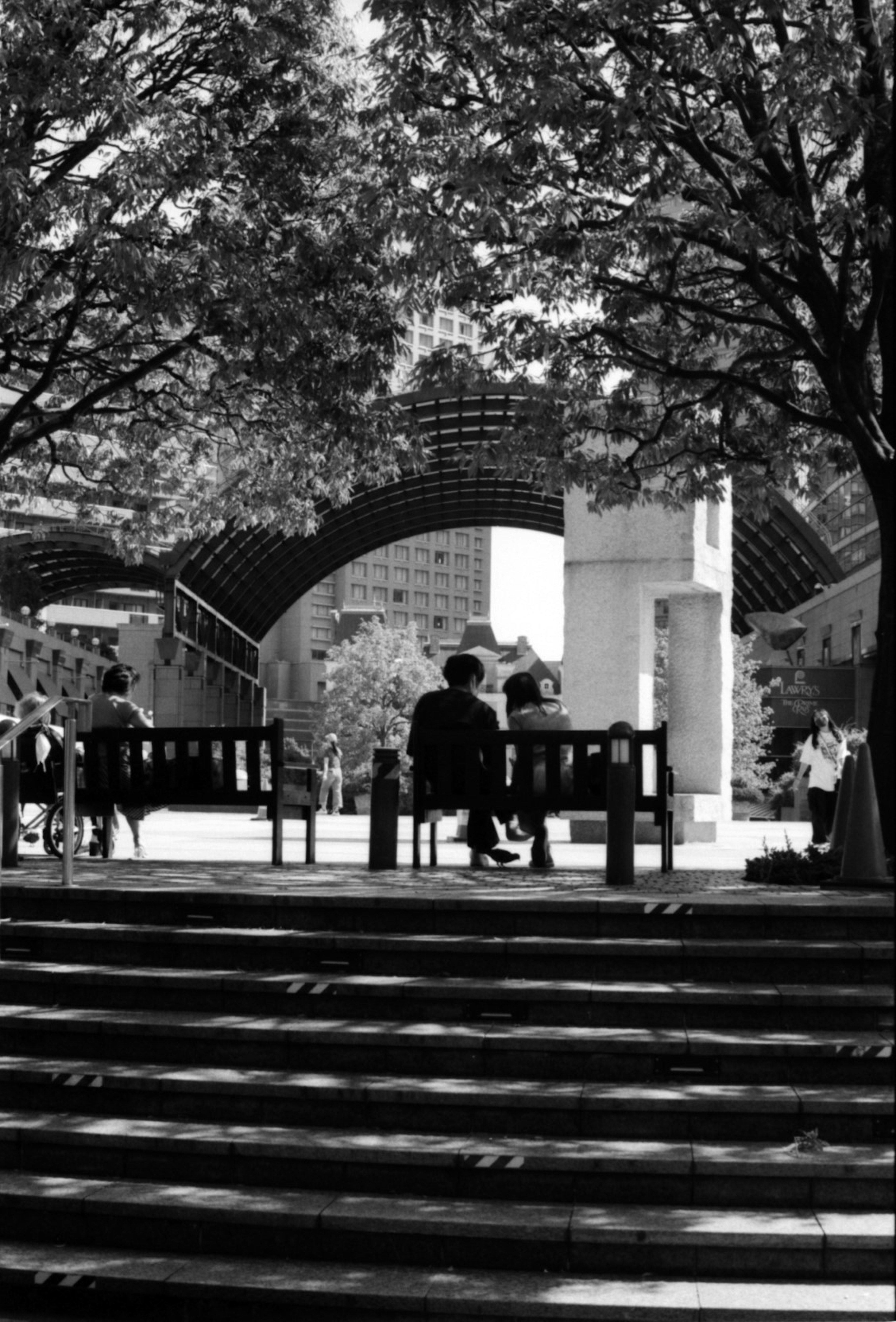 People sitting on stairs in a park with a building in the background