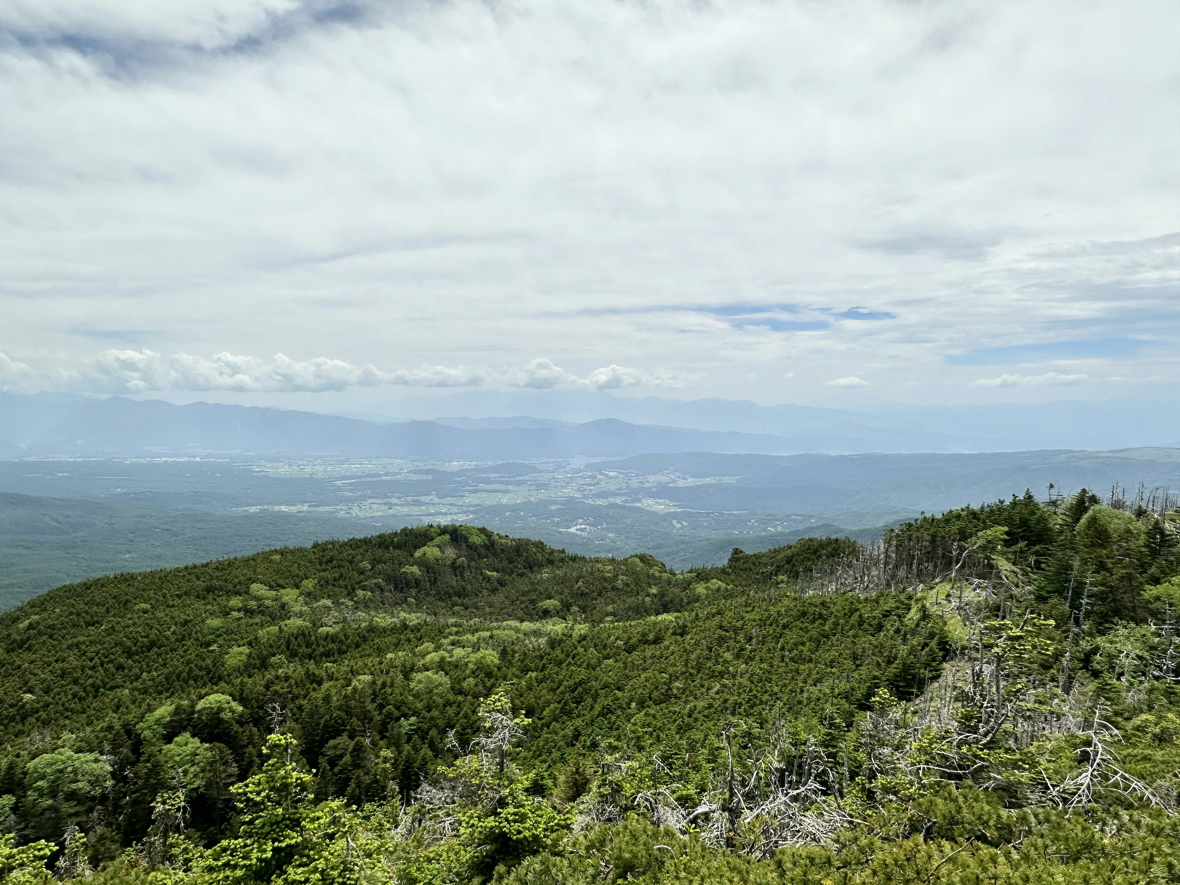 Lush green mountain landscape with distant mountains visible