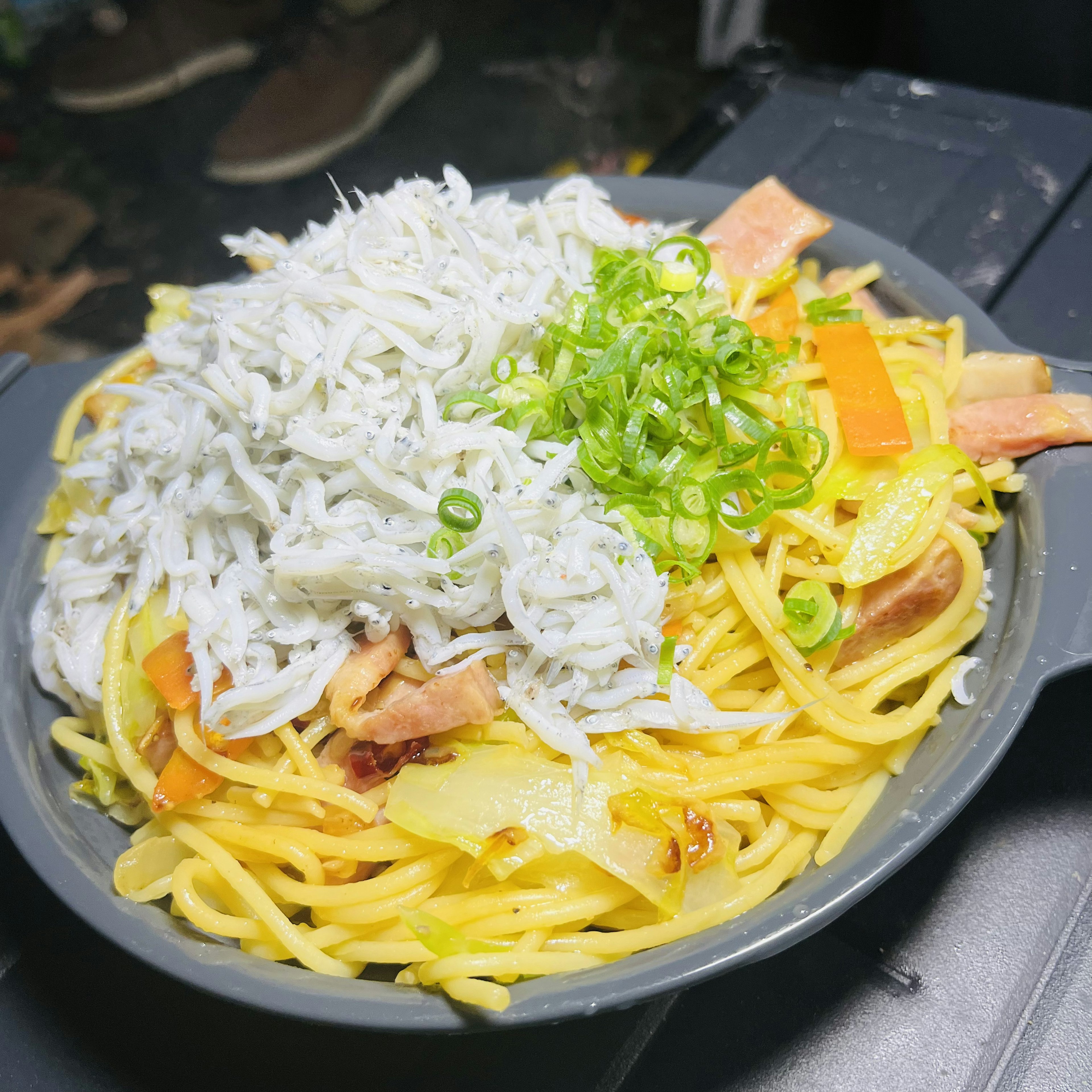 Stir-fried noodles topped with shredded white fish and green onions