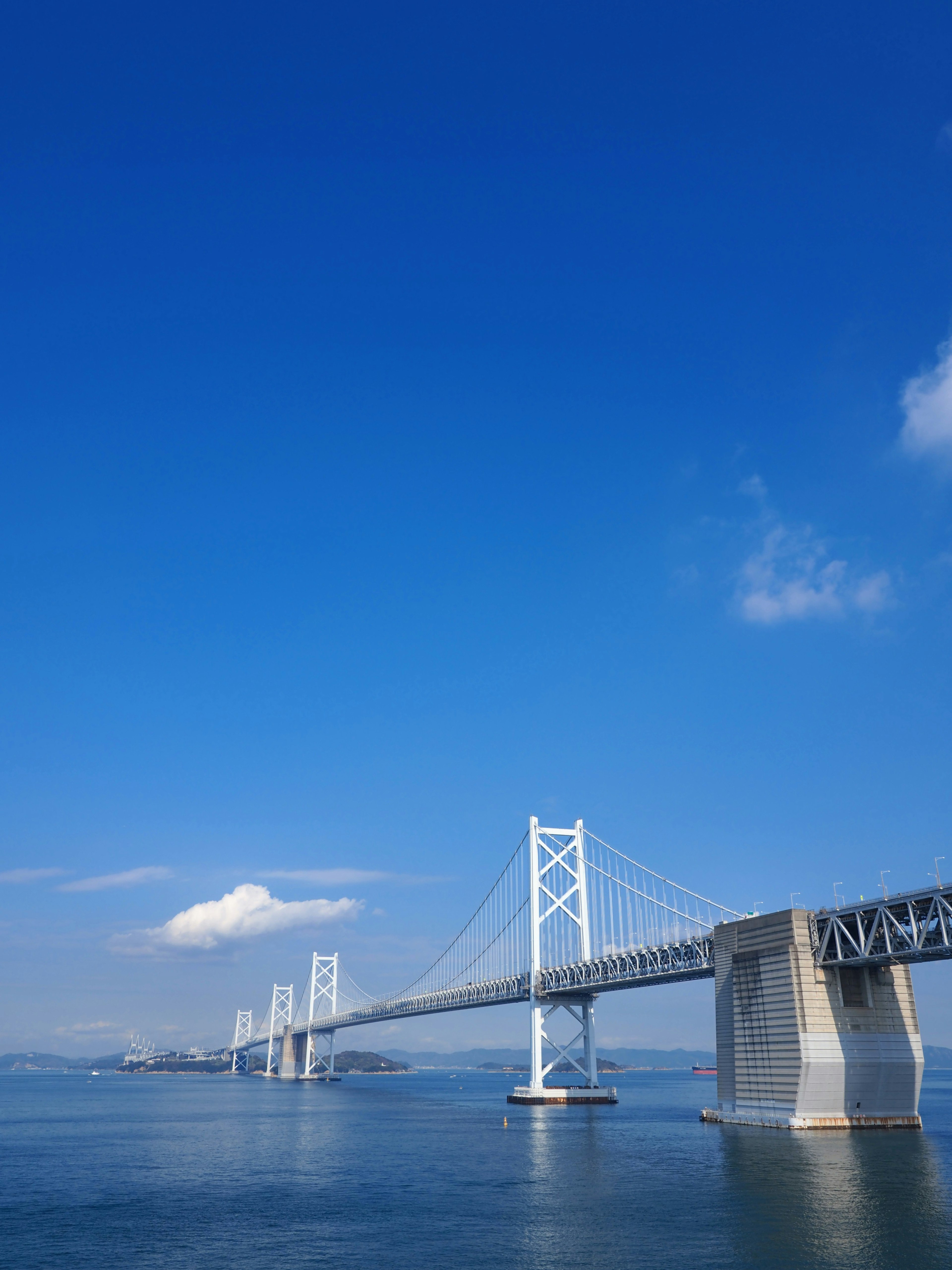 Pont blanc s'étendant sur des eaux calmes sous un ciel bleu