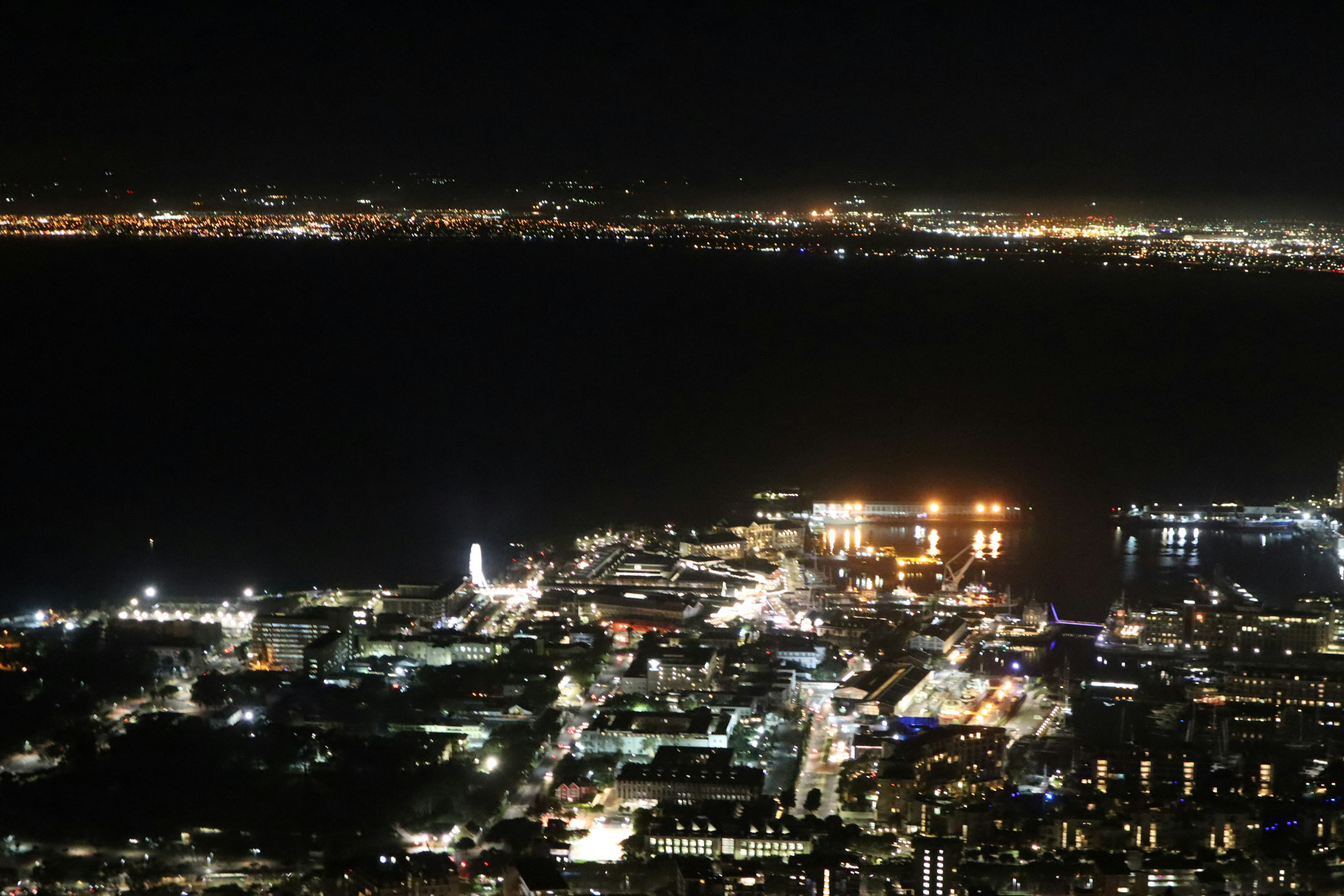 Vista nocturna de una ciudad costera iluminada por luces