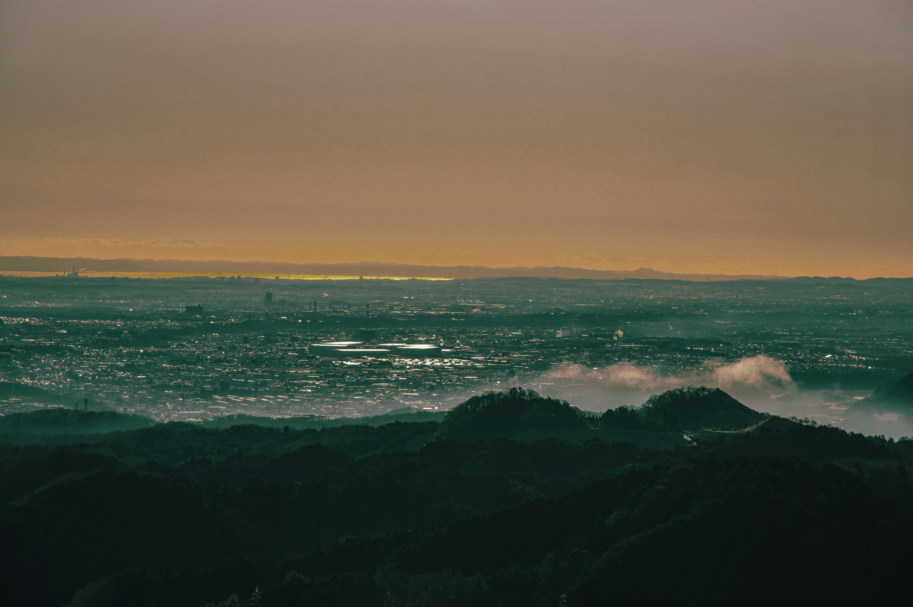 Pemandangan panorama kota saat senja dengan pegunungan berkabut