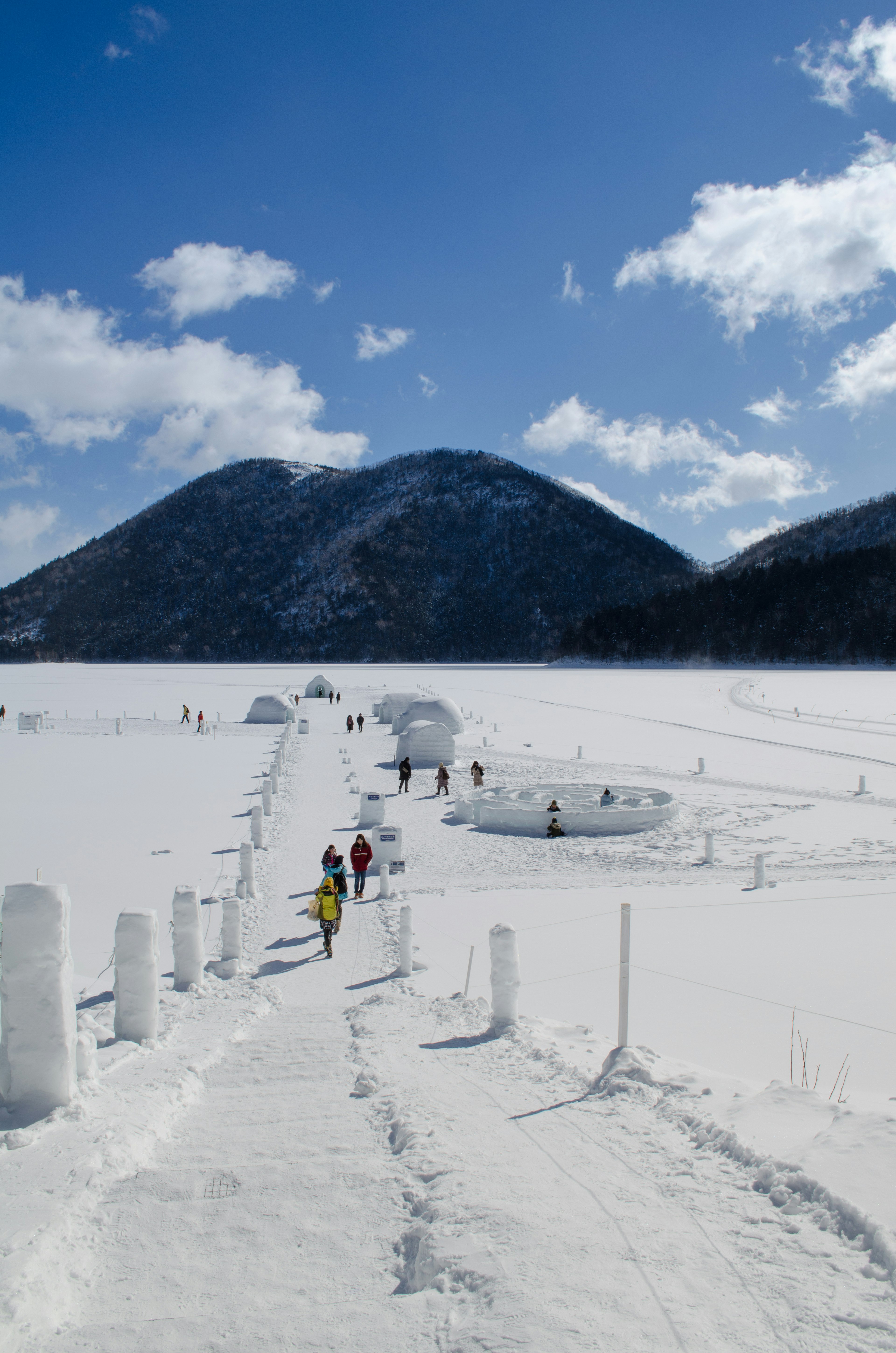 People walking through a snowy landscape with mountains in the background