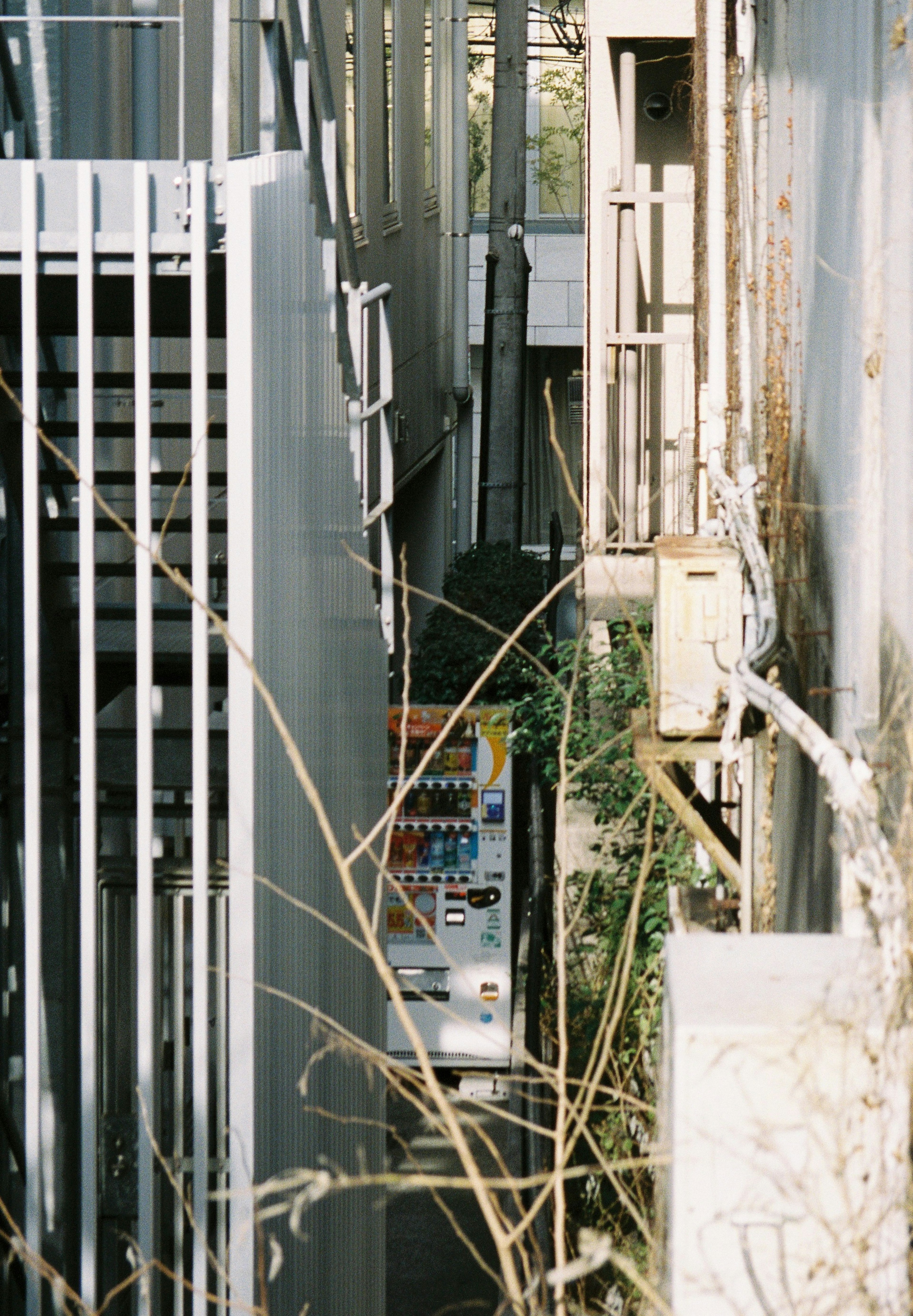 Un callejón estrecho con una máquina expendedora y estructuras de edificios circundantes