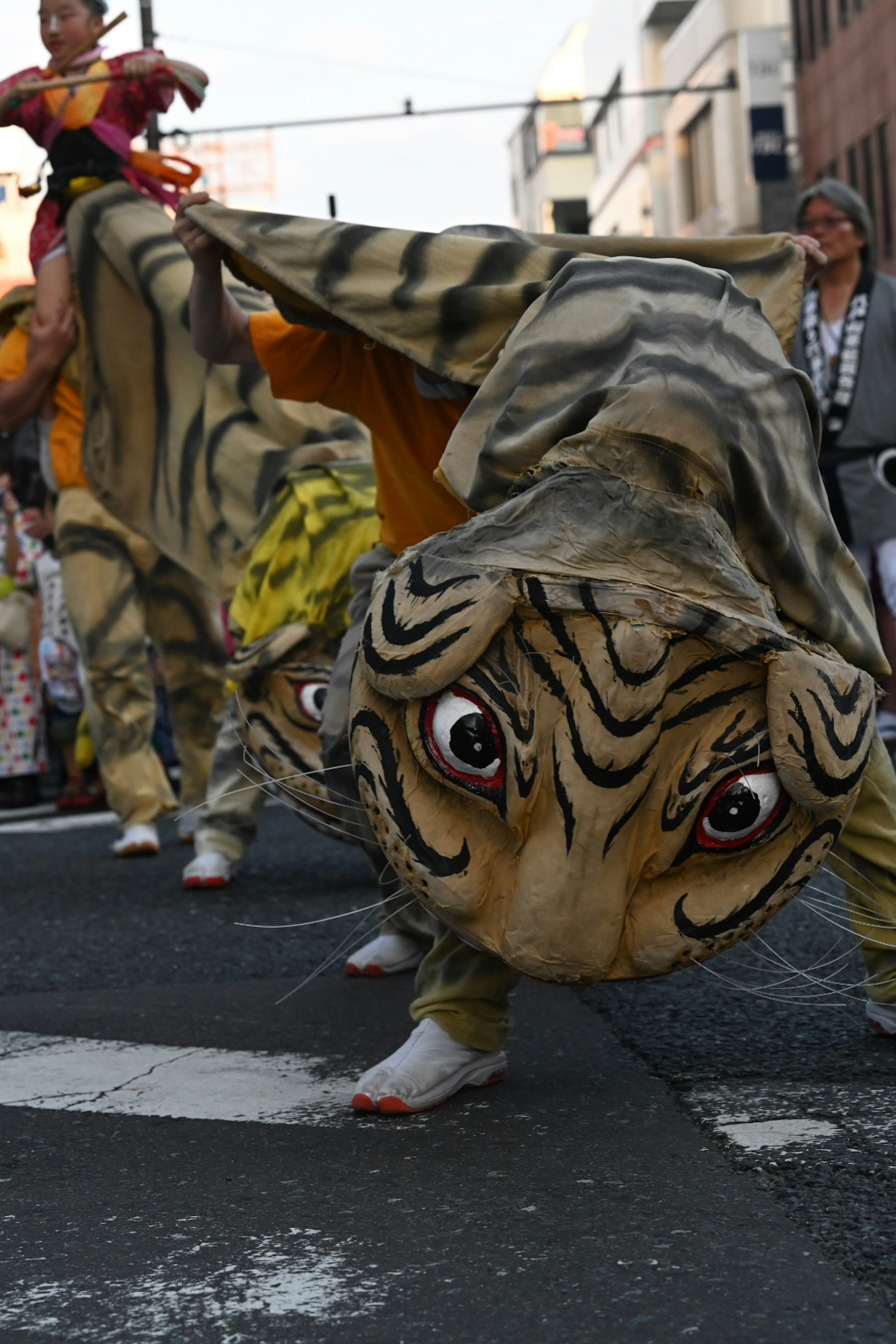 Character in a tiger costume performing in a parade with a vibrant background