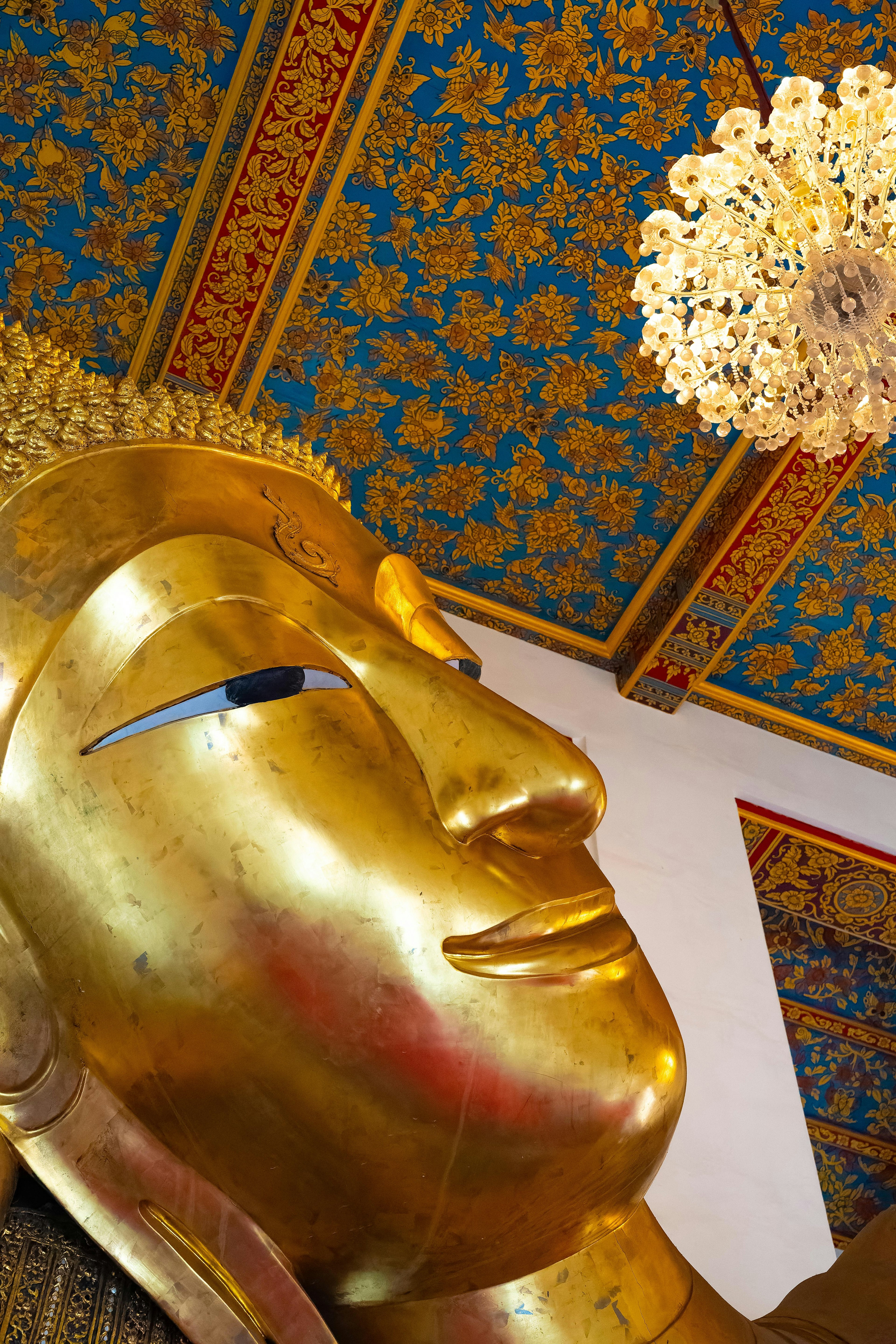 Side view of a golden Buddha statue with ornate ceiling design