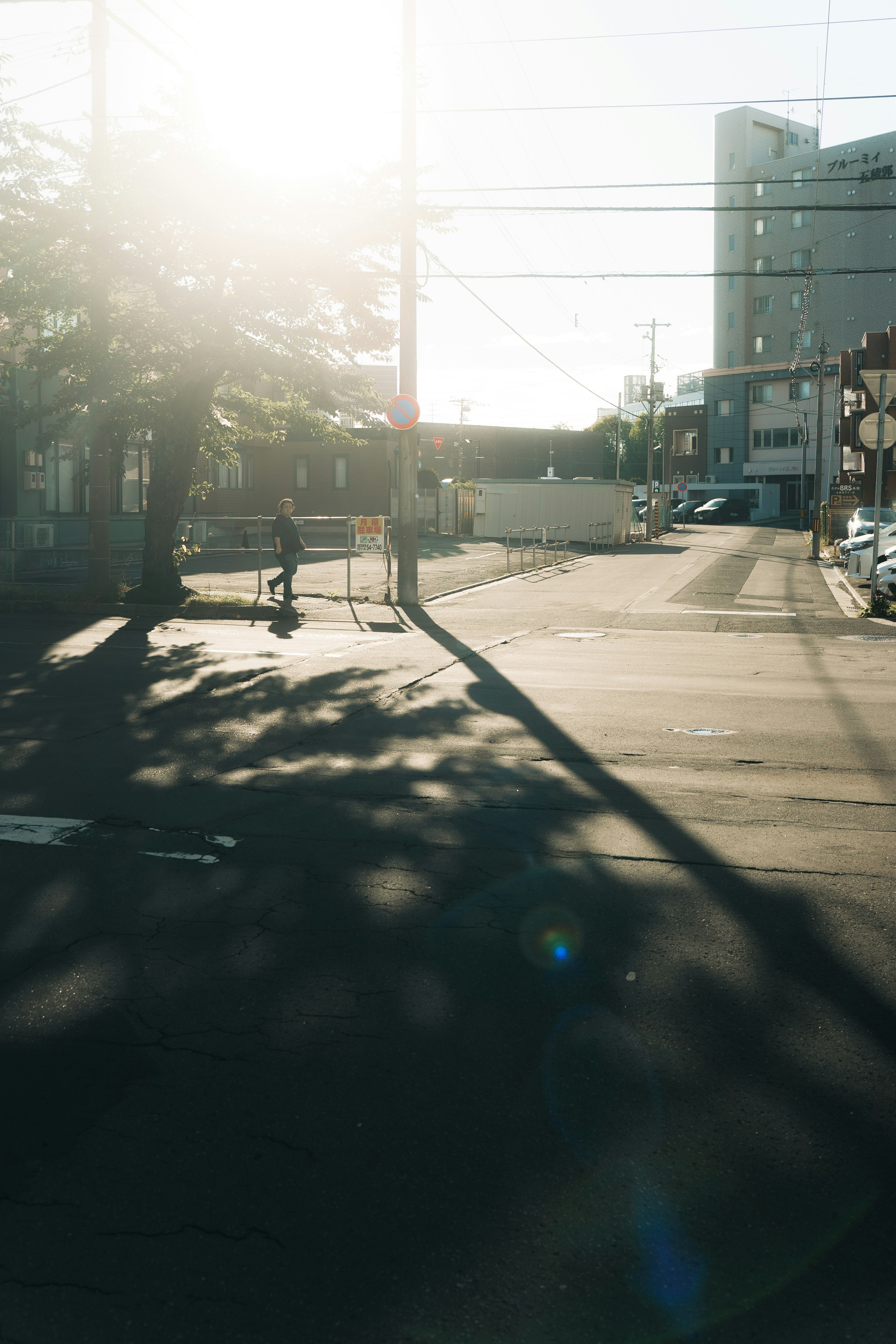 People walking at a quiet street corner under bright sunlight