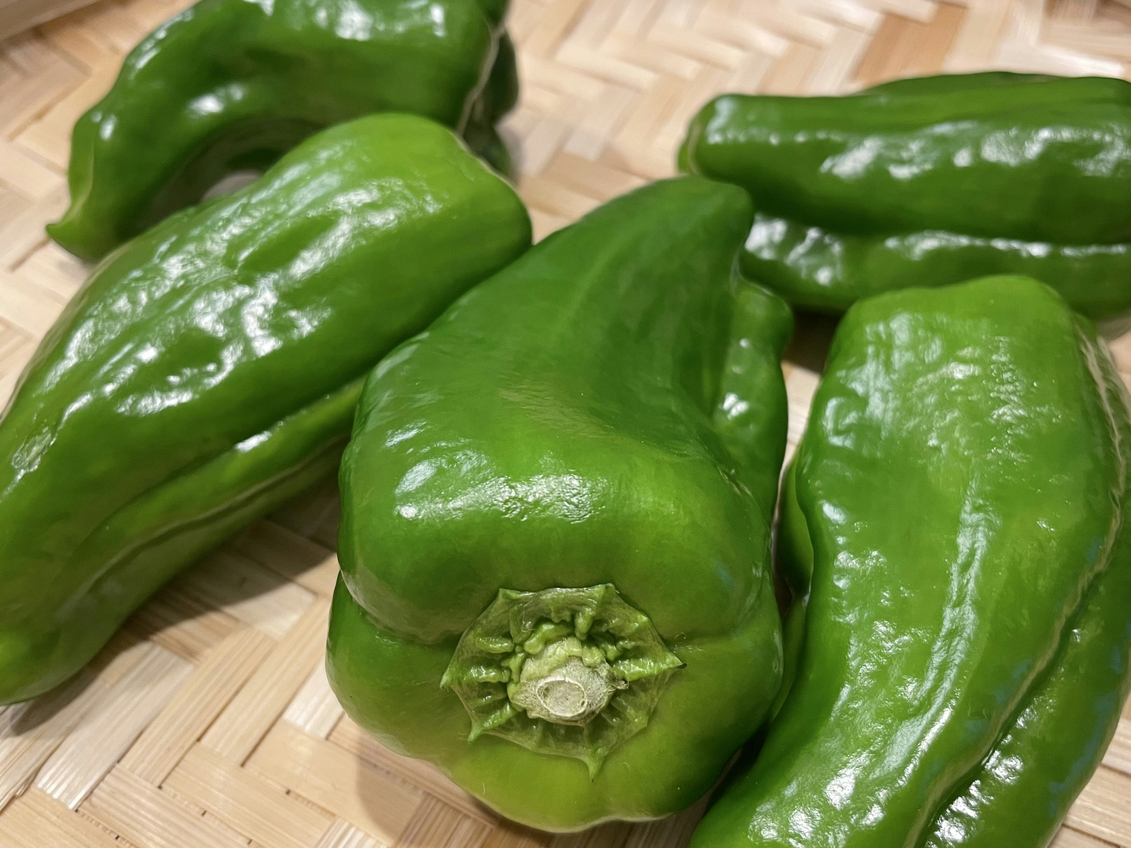 Fresh green peppers arranged on a woven surface