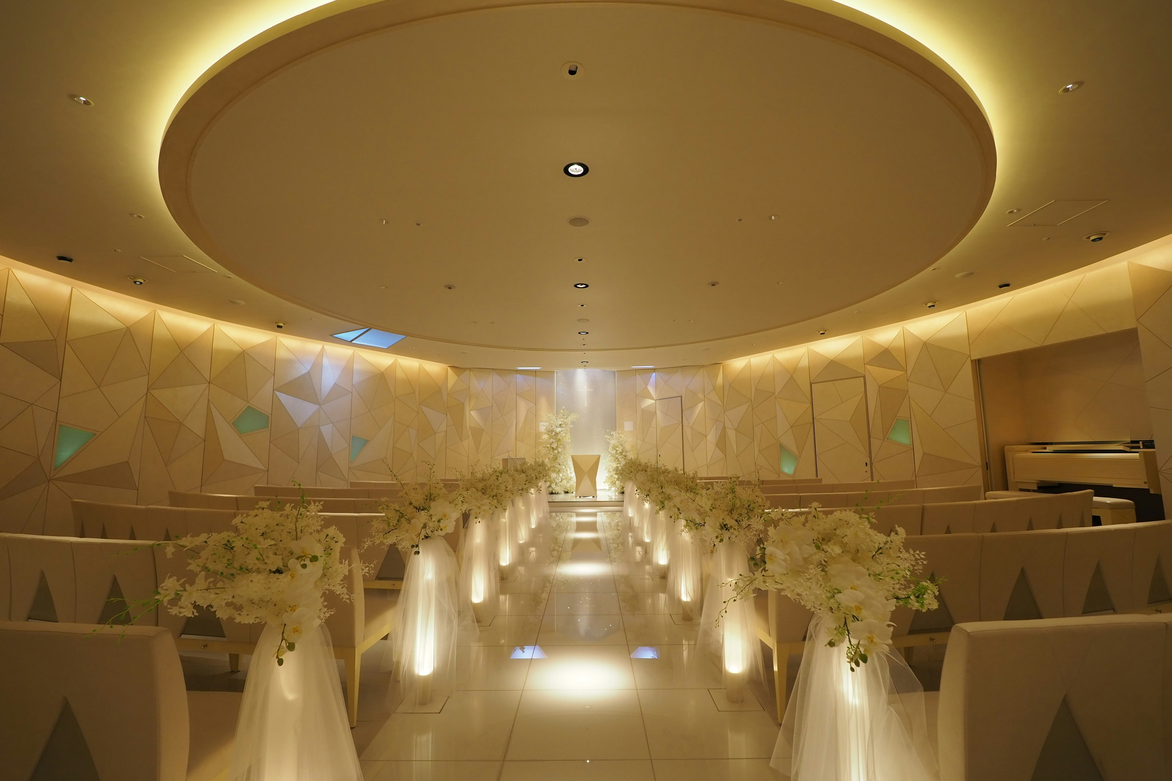 Brightly lit wedding venue with white floral decorations and elegant seating