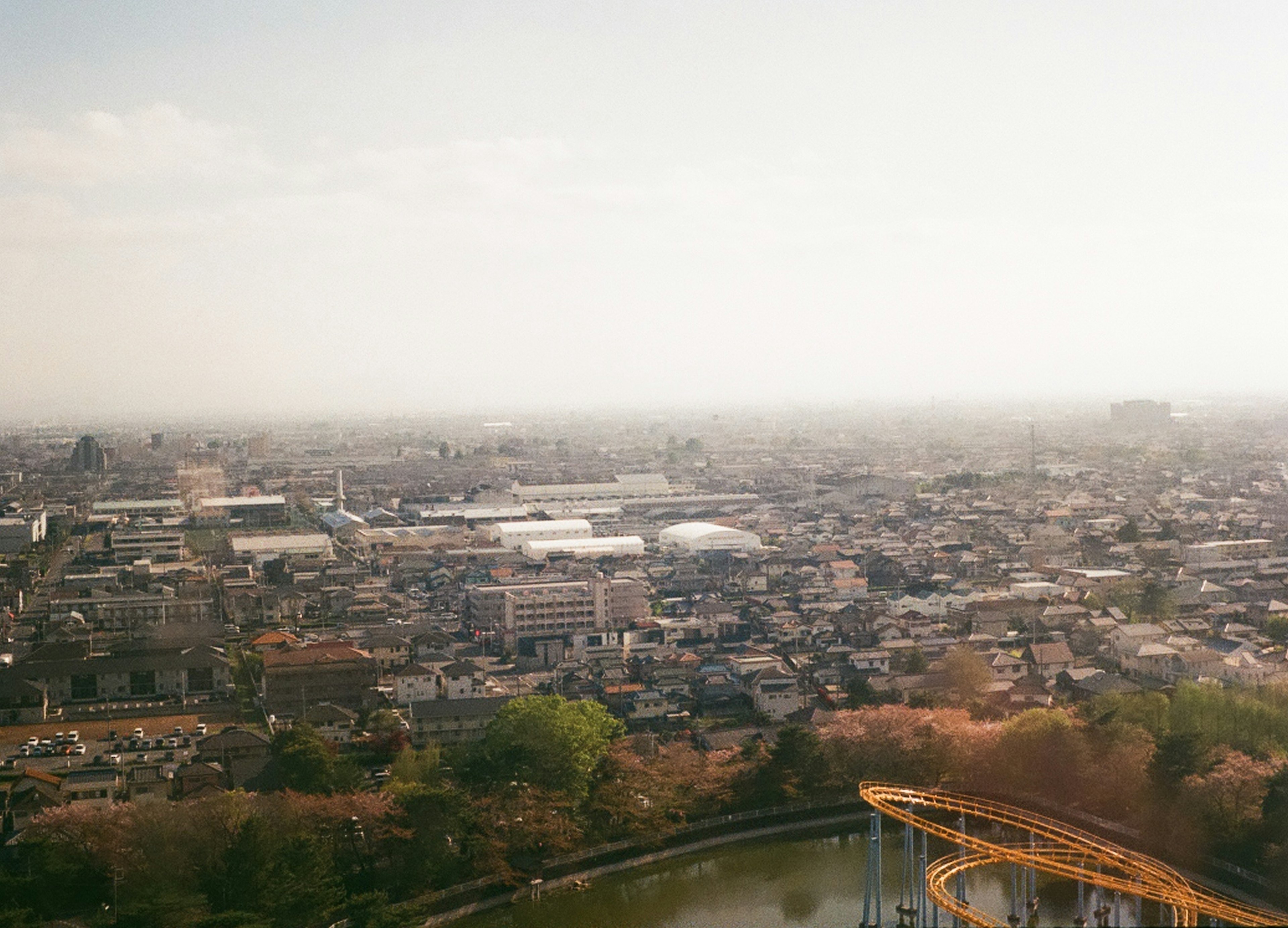 Aerial view of a cityscape featuring greenery and a roller coaster