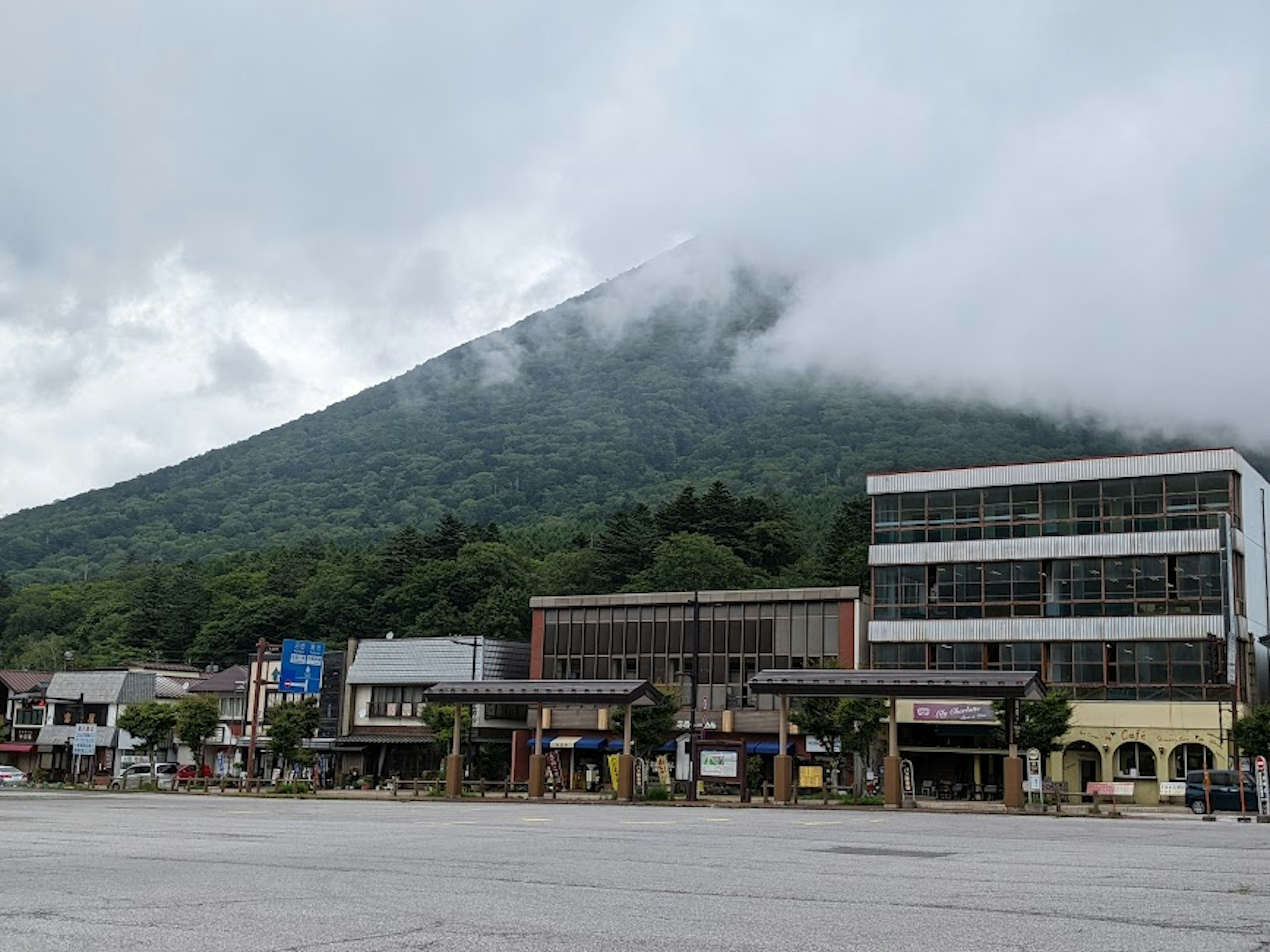 Pemandangan gunung yang diselimuti kabut dengan bangunan komersial di latar depan