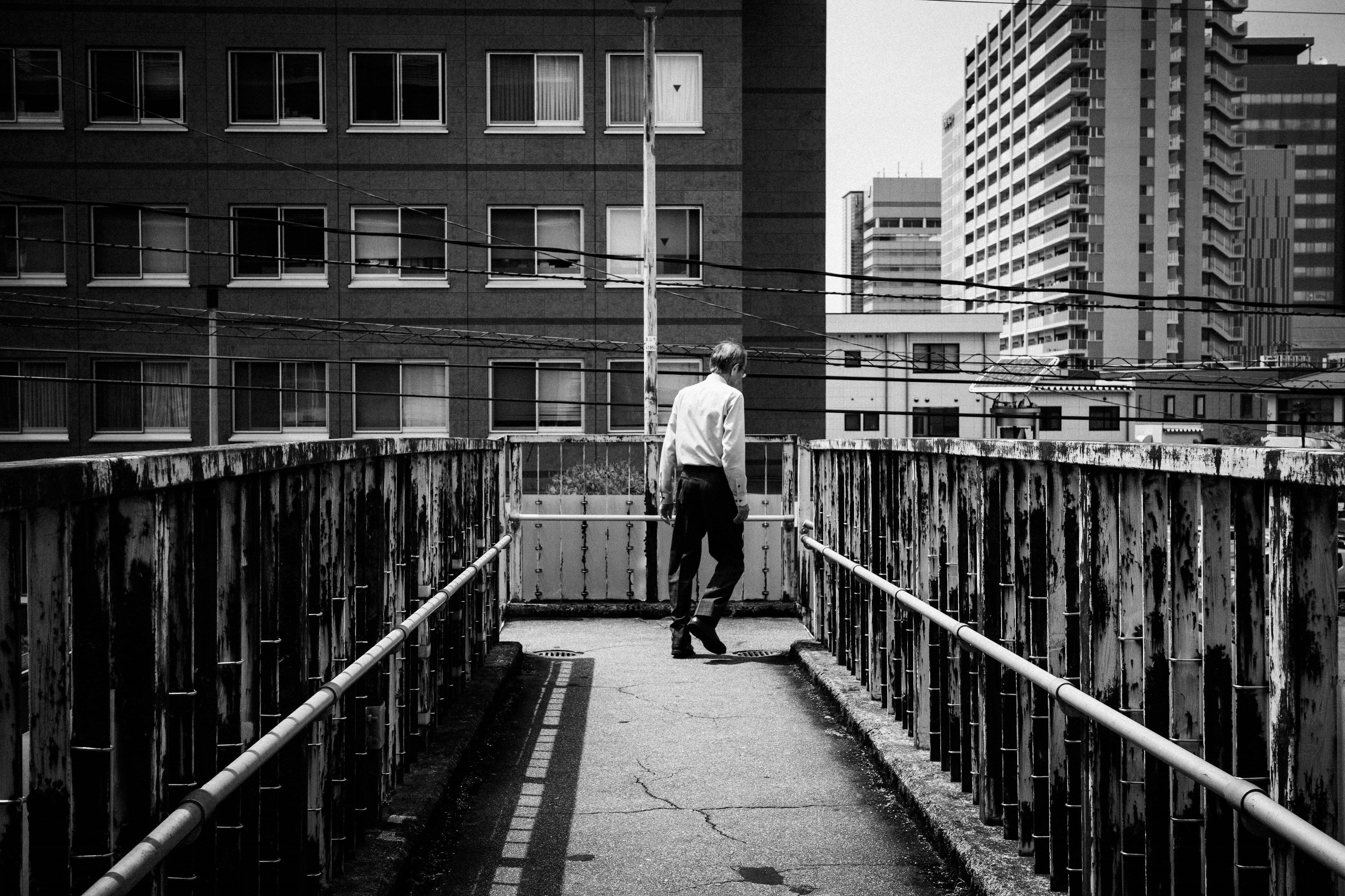 Man walking on a bridge in a black and white urban setting