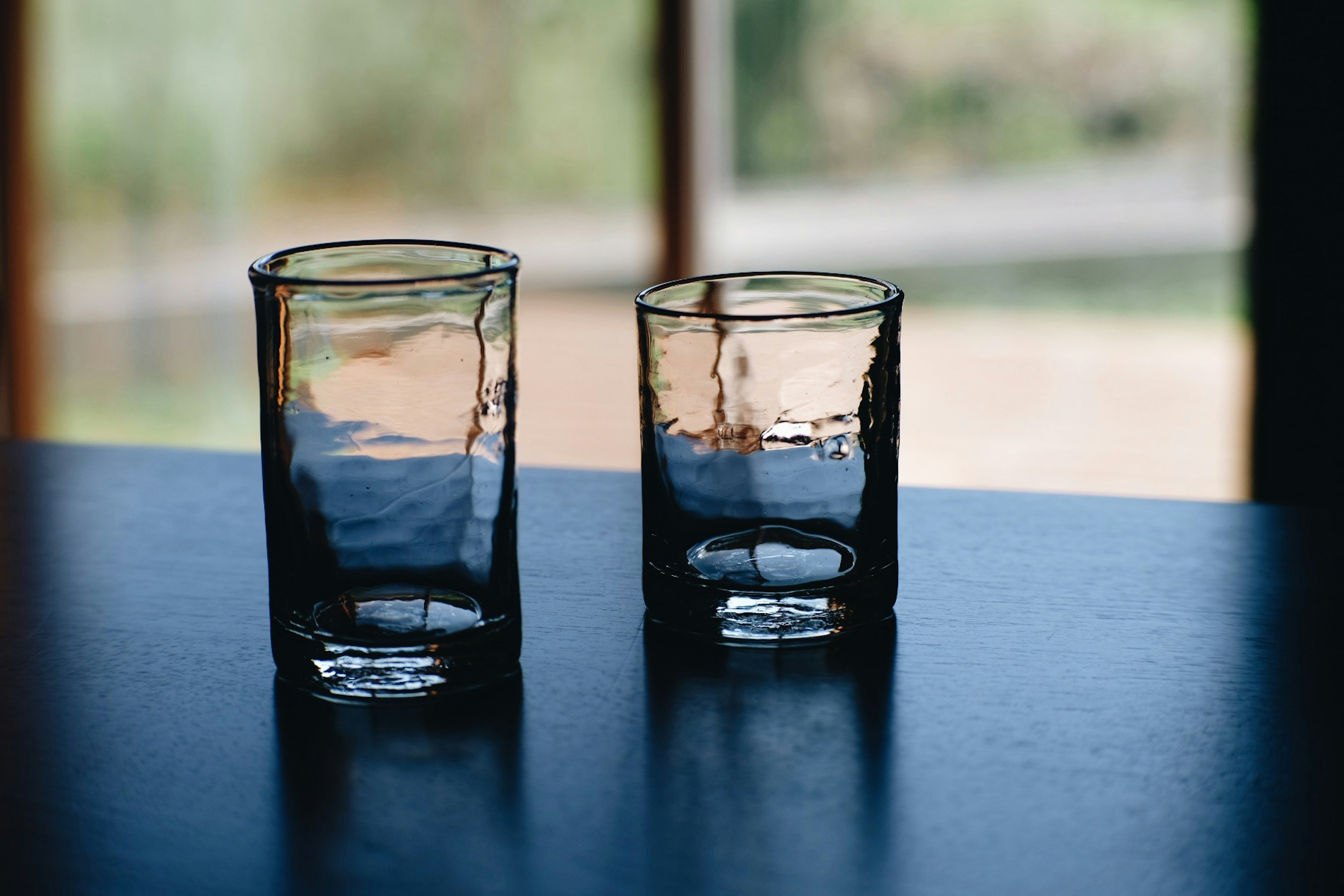 Two transparent glasses on a table with a blurred background