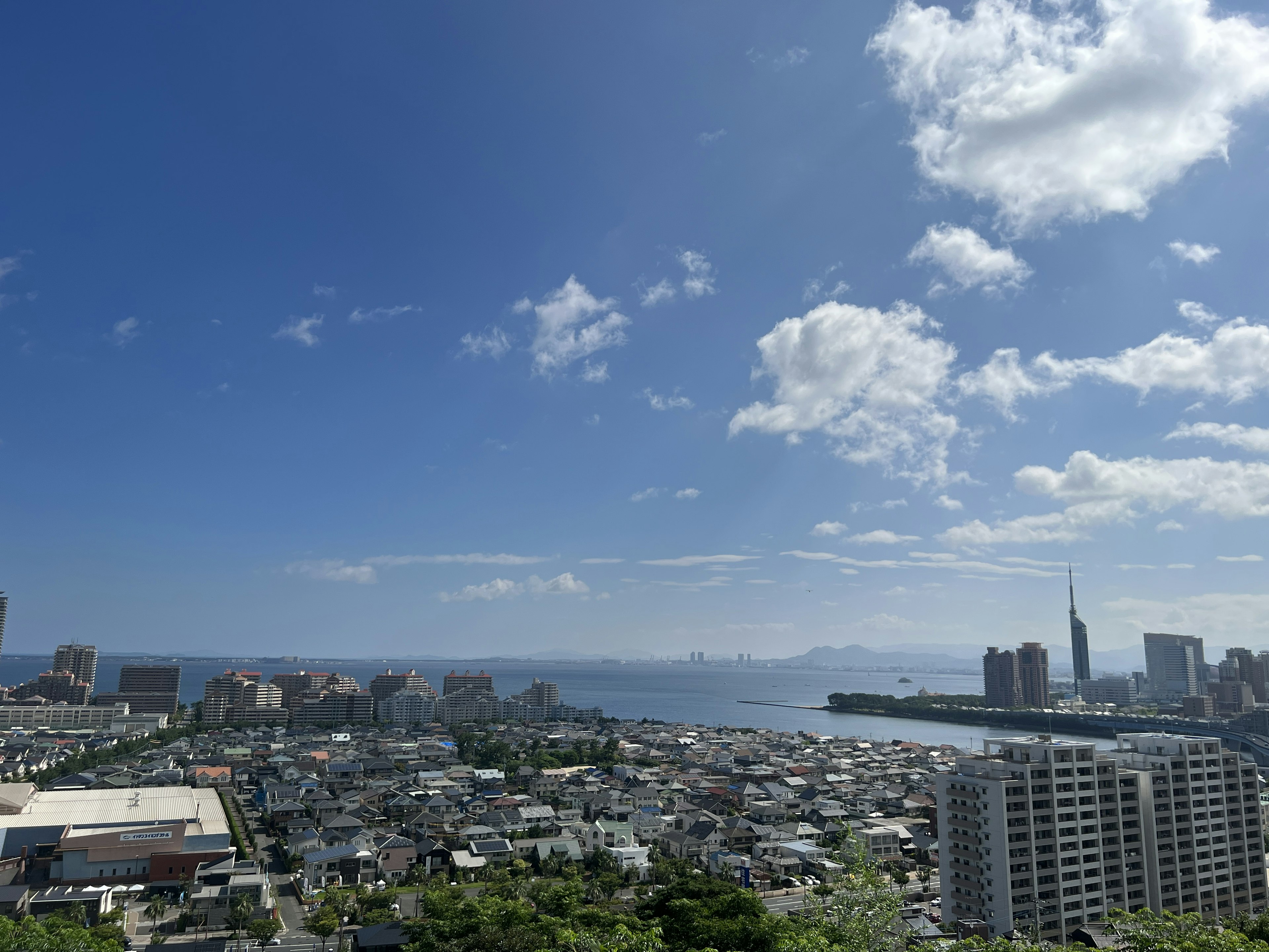 青い空と雲の下に広がる都市の景色海とビルが見える