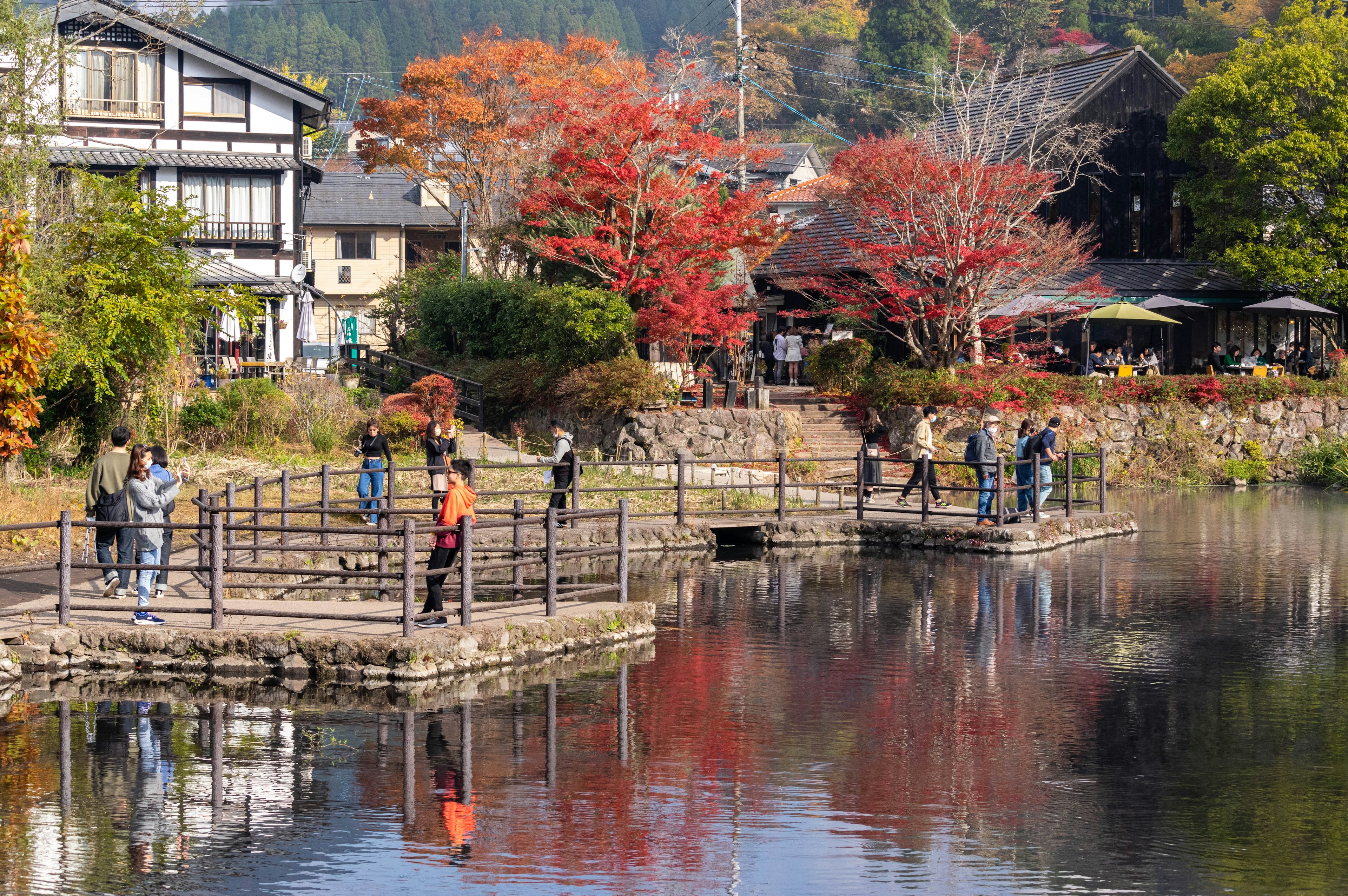 Scenic view of a lake reflecting autumn foliage with people walking