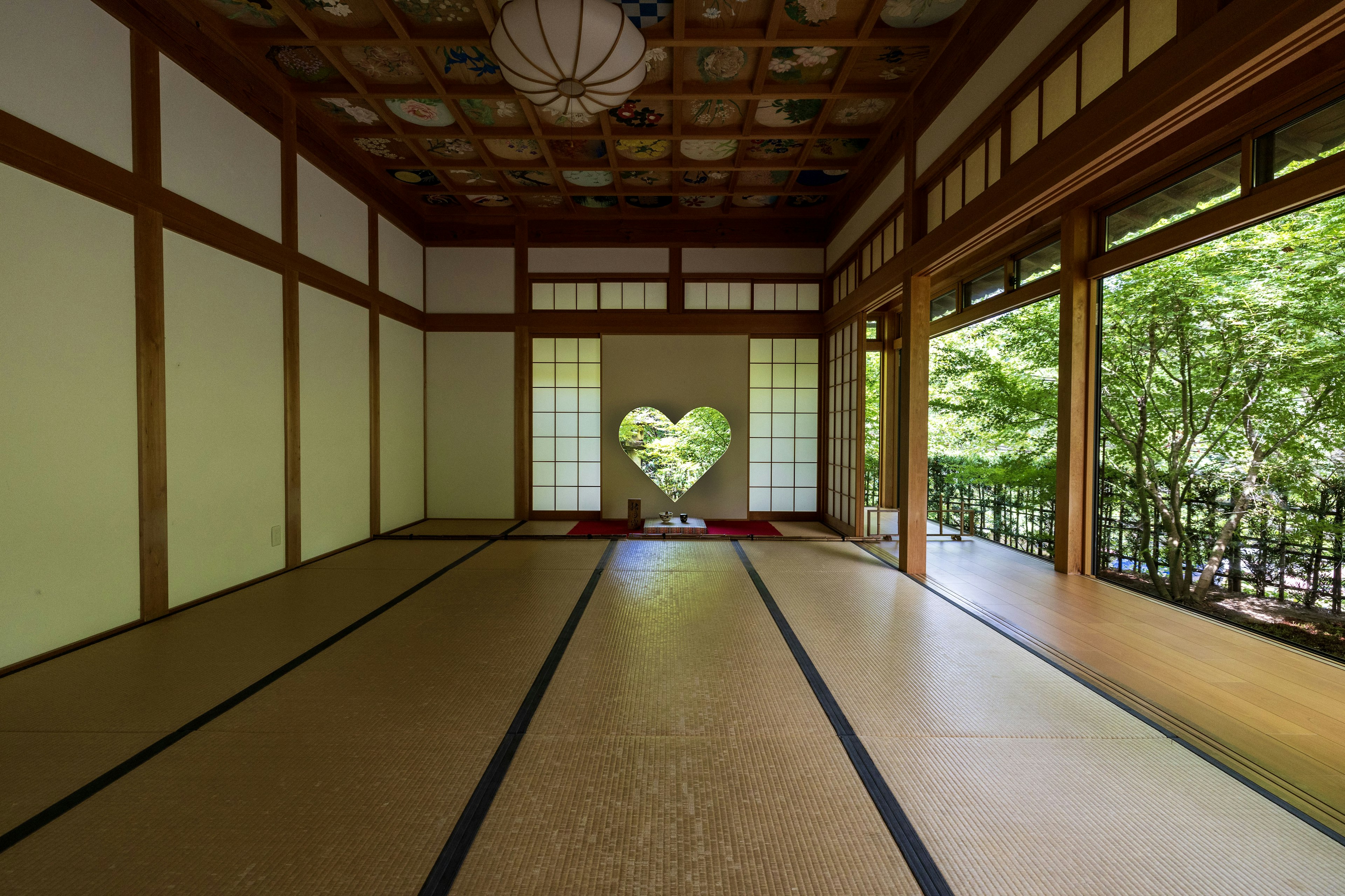 A tranquil Japanese room featuring a heart-shaped window with a view of greenery