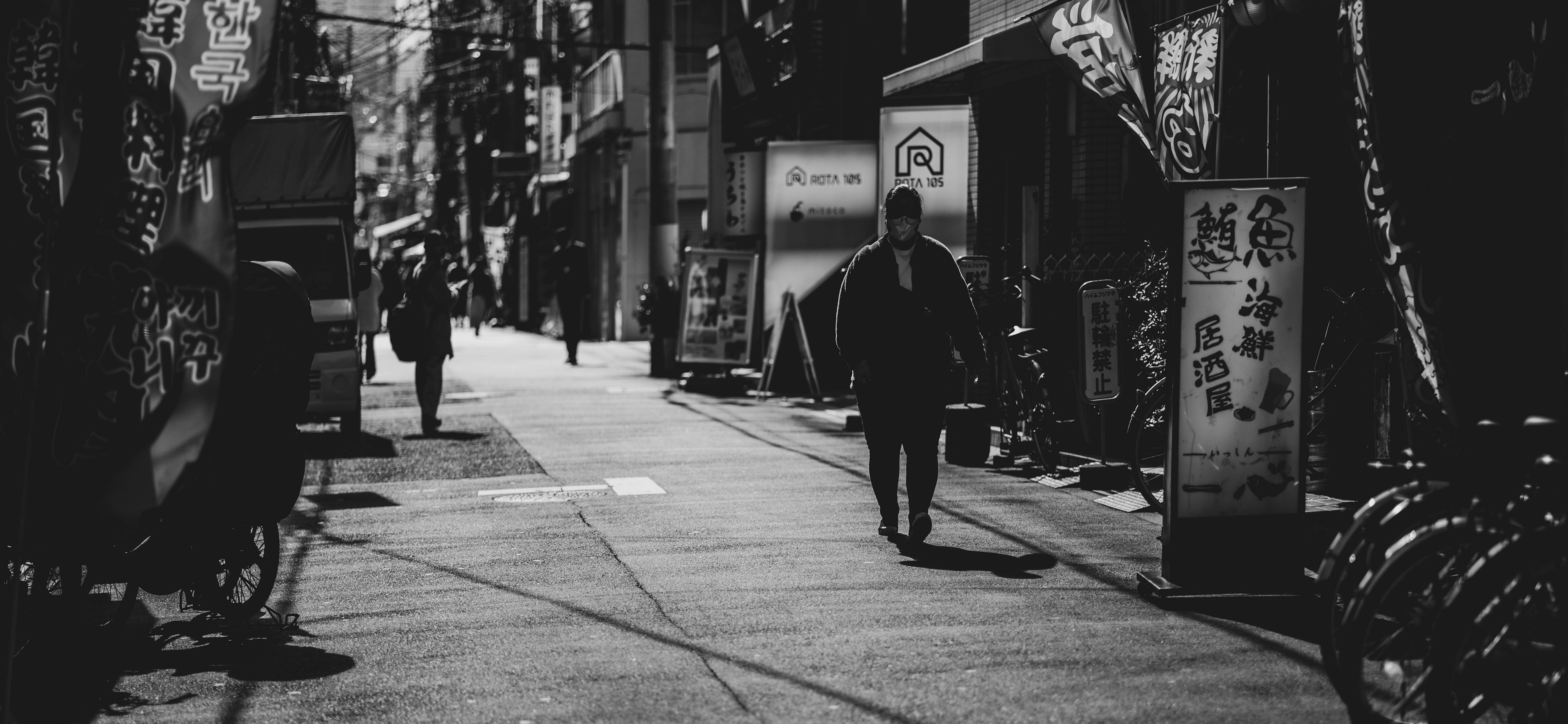 人々が歩く静かな街路のモノクロ写真