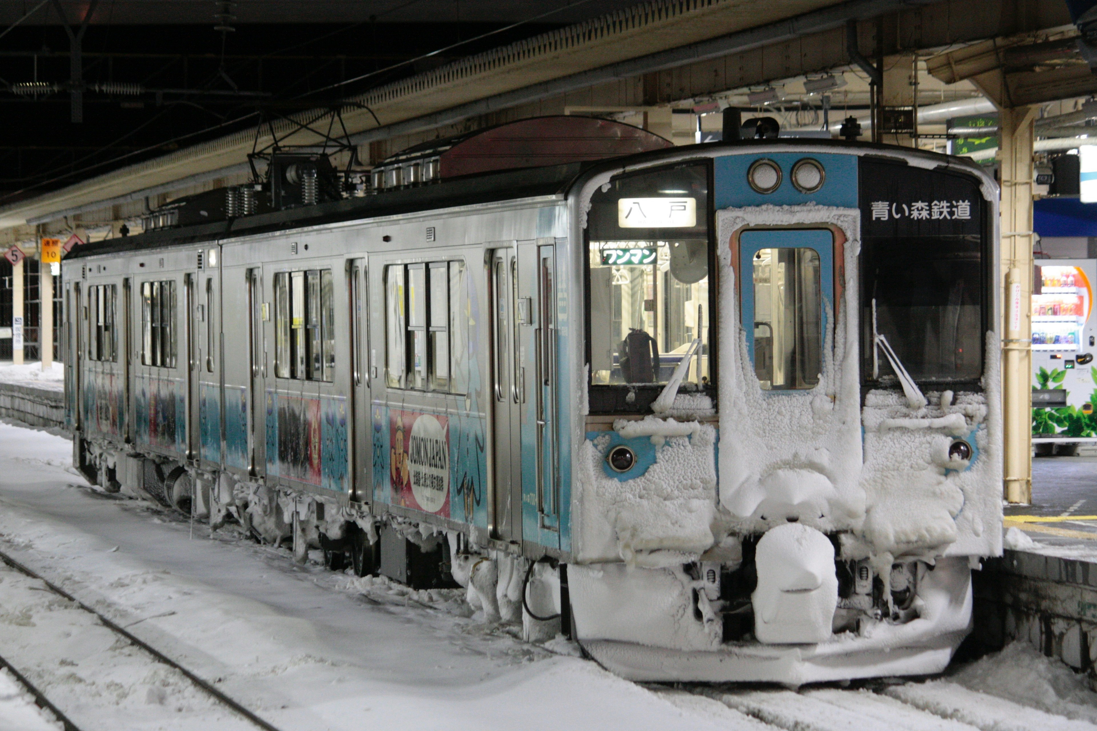 Un train recouvert de neige garé à une station