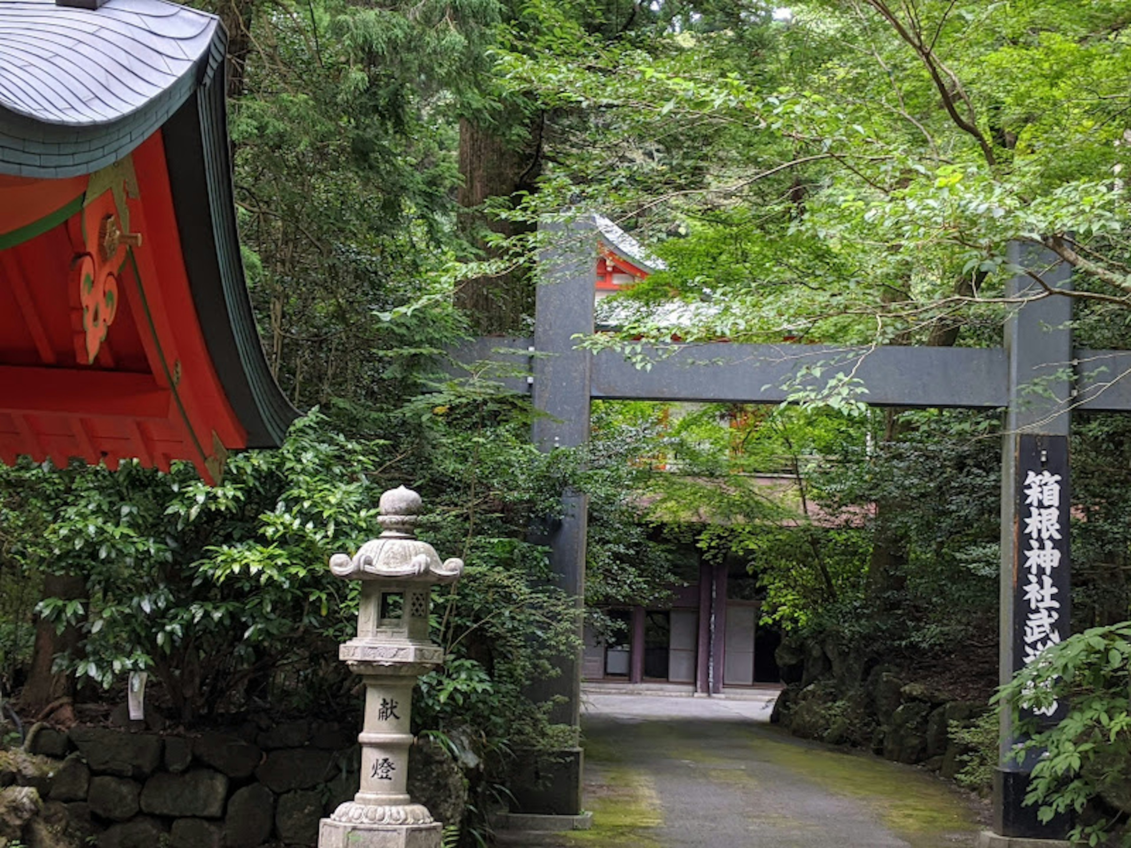 Entrance of a shrine surrounded by lush greenery and a stone lantern