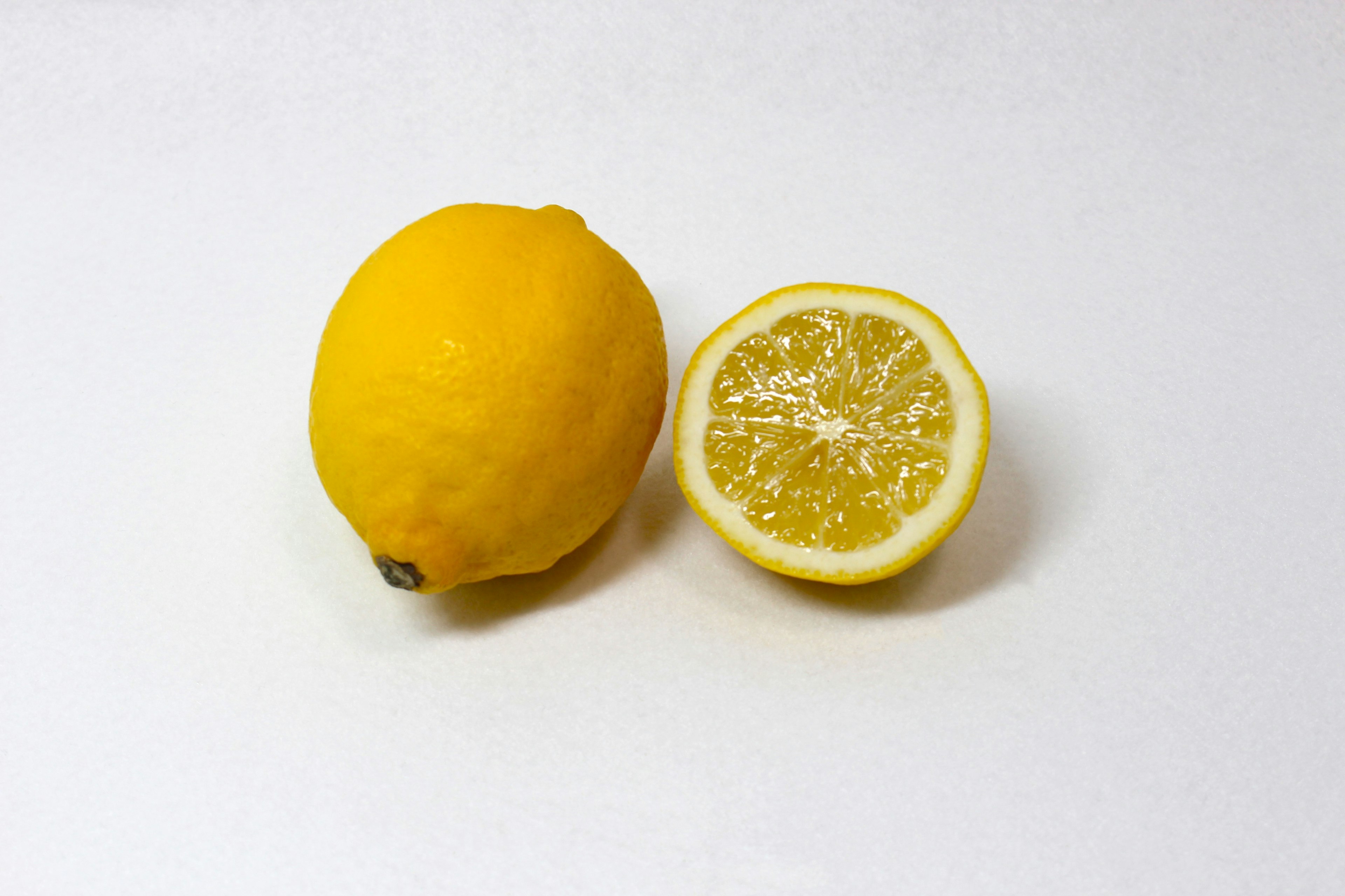 A whole lemon and a sliced lemon half on a white background