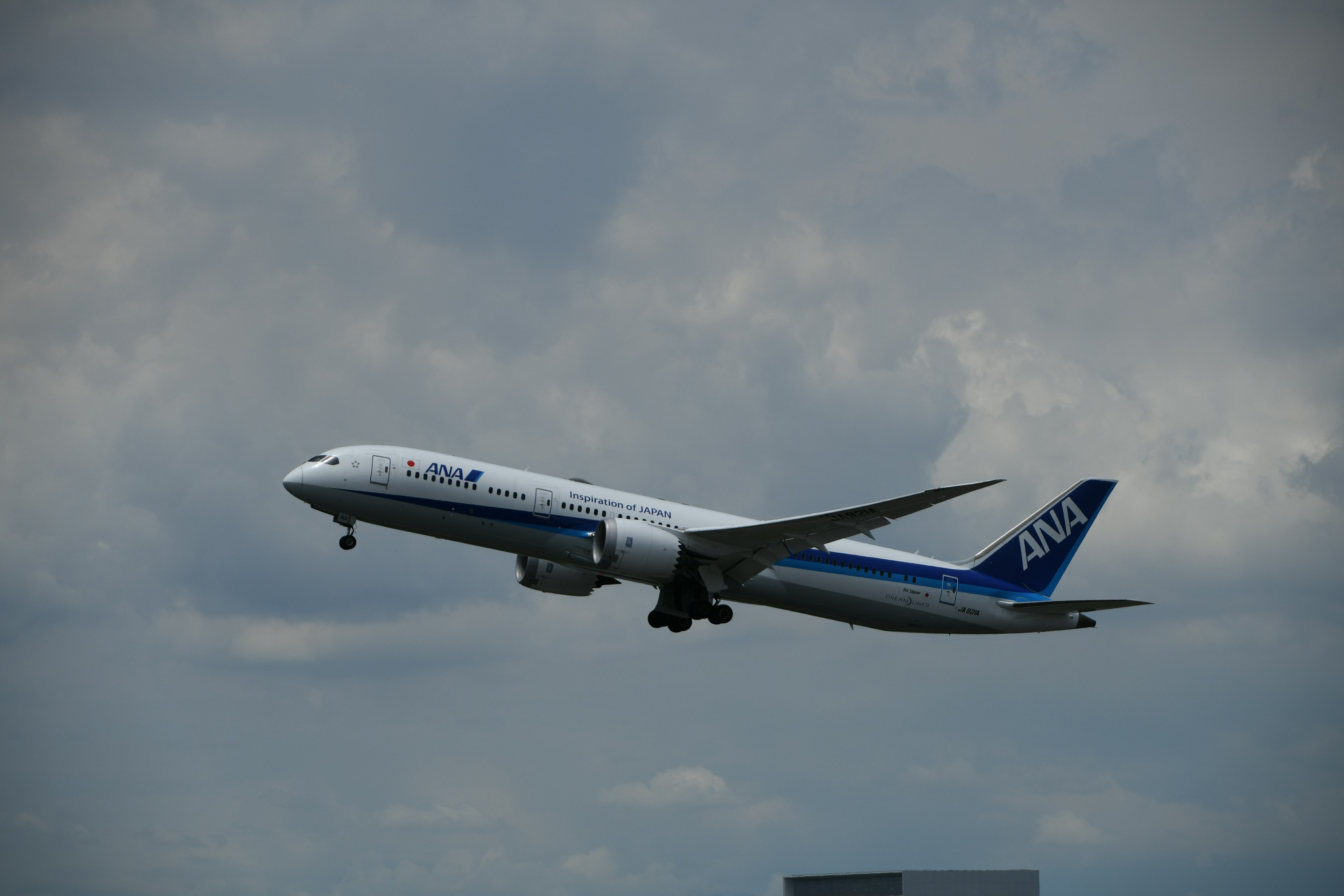 Boeing 787 de ANA volando contra un cielo nublado