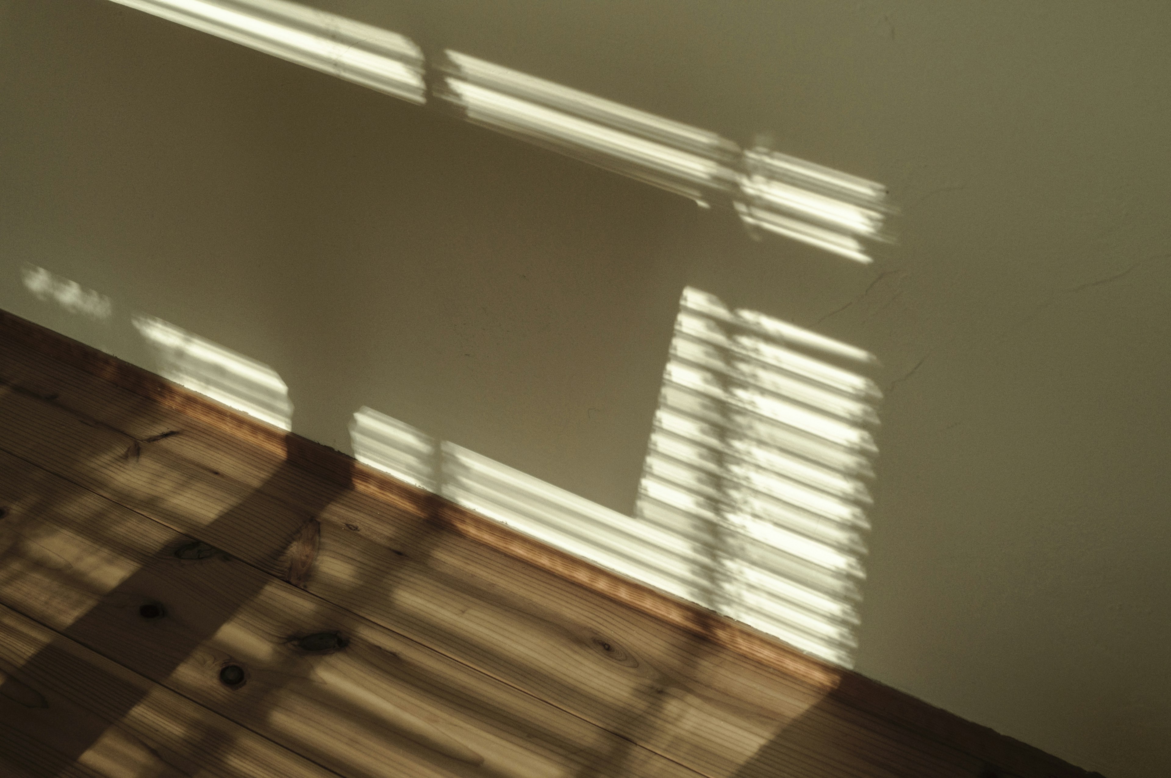 Escena interior con sombras proyectadas en una pared por persianas de madera