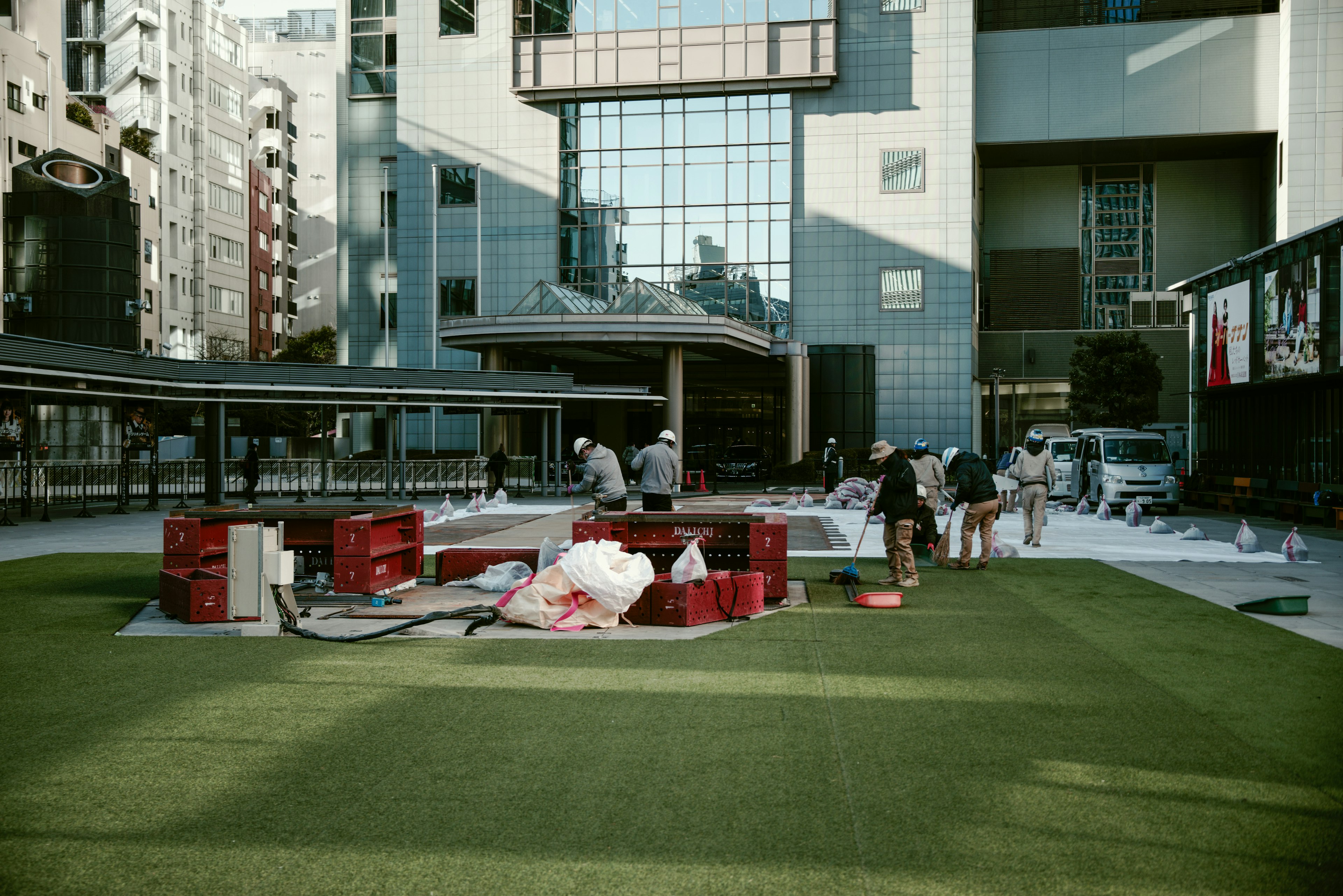 People working in an urban plaza with green grass