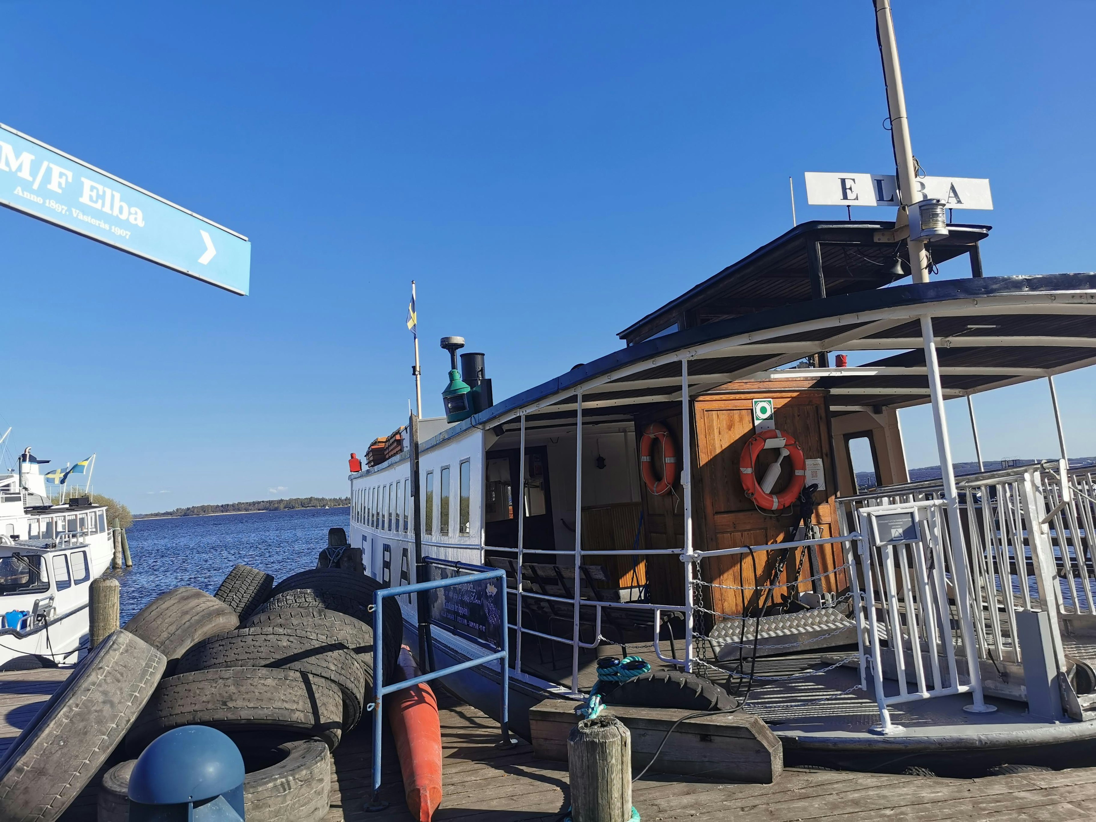 A docked ferry with a blue sky and surrounding harbor