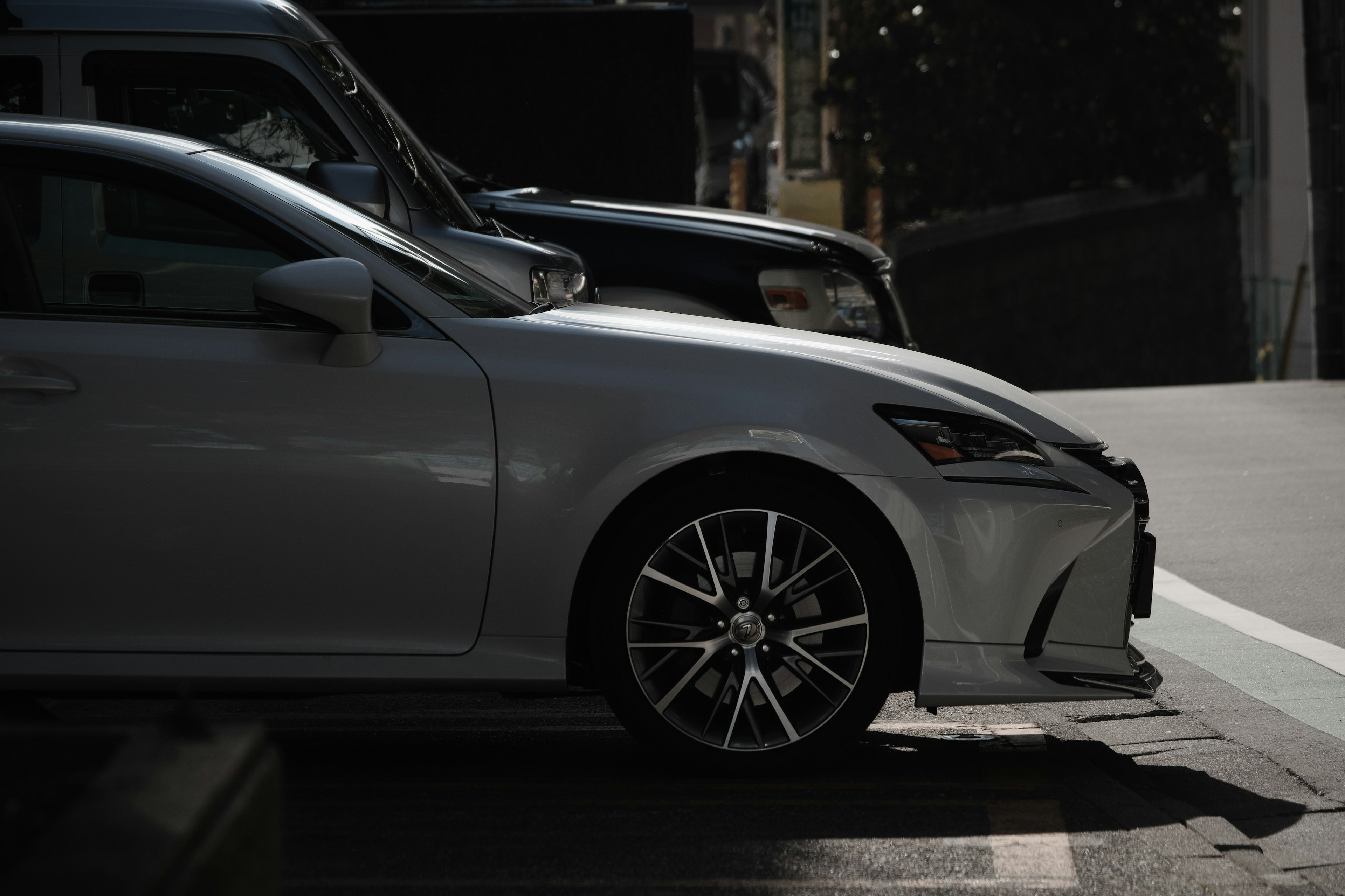 Side view of a silver car parked next to a black car in a parking area