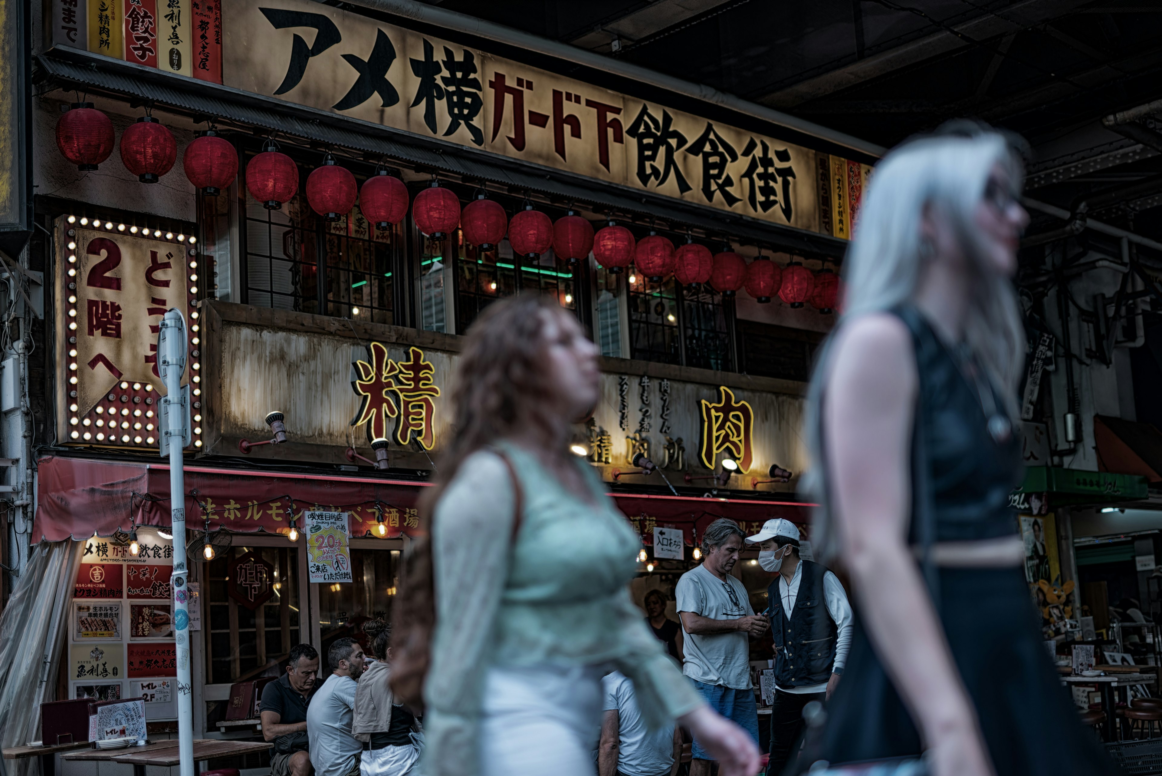 Busy street scene with people walking by food stalls Bright red lanterns and traditional signage are prominent