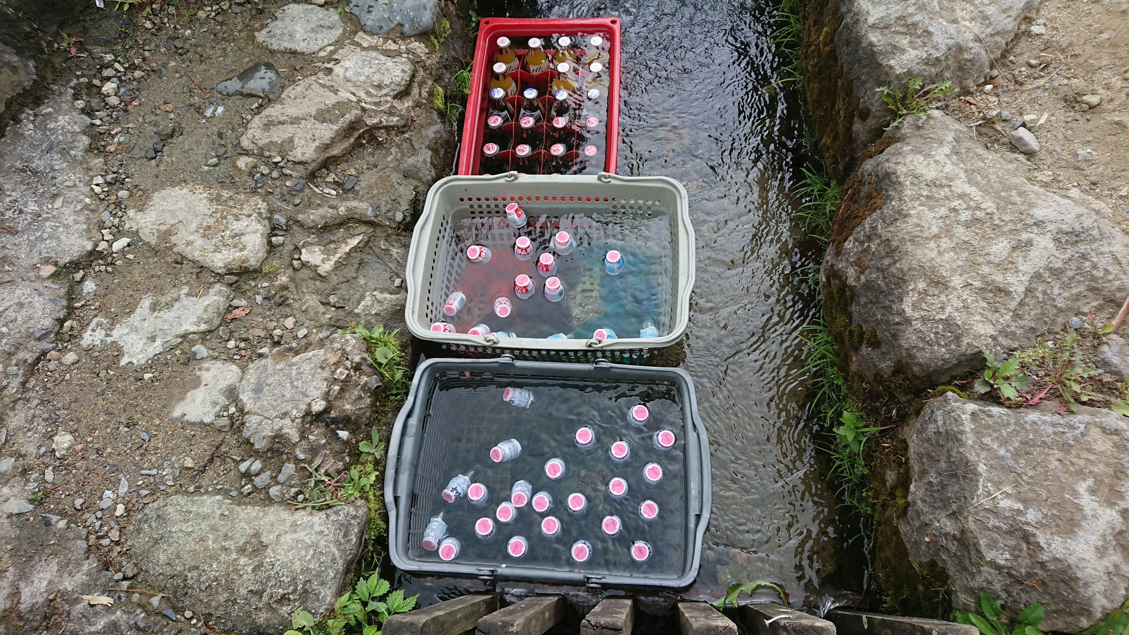 Bunte Behälter mit floralen Dekorationen im fließenden Wasser platziert