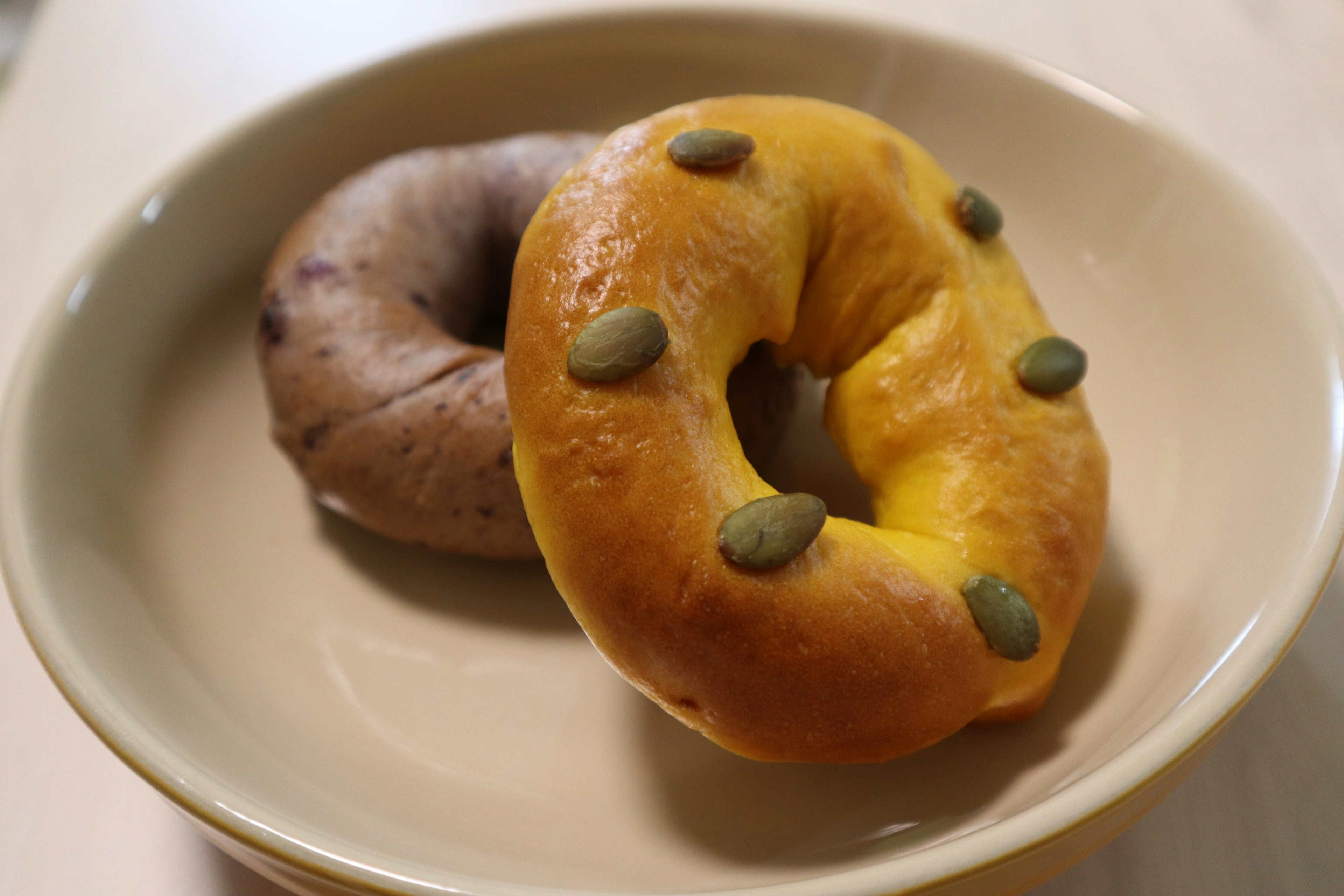 Deux bagels de couleurs orange et violet sur une assiette