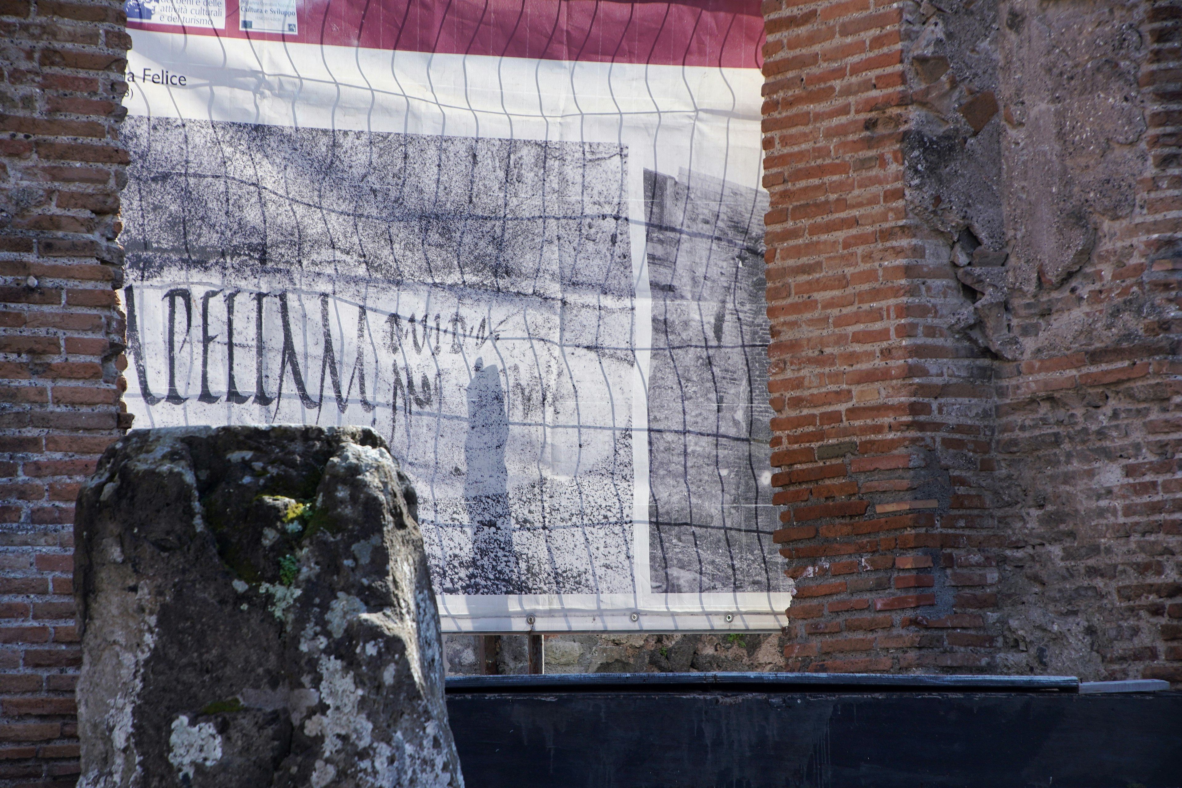 Part of a wall covered with netting in an ancient ruin with a stone pillar