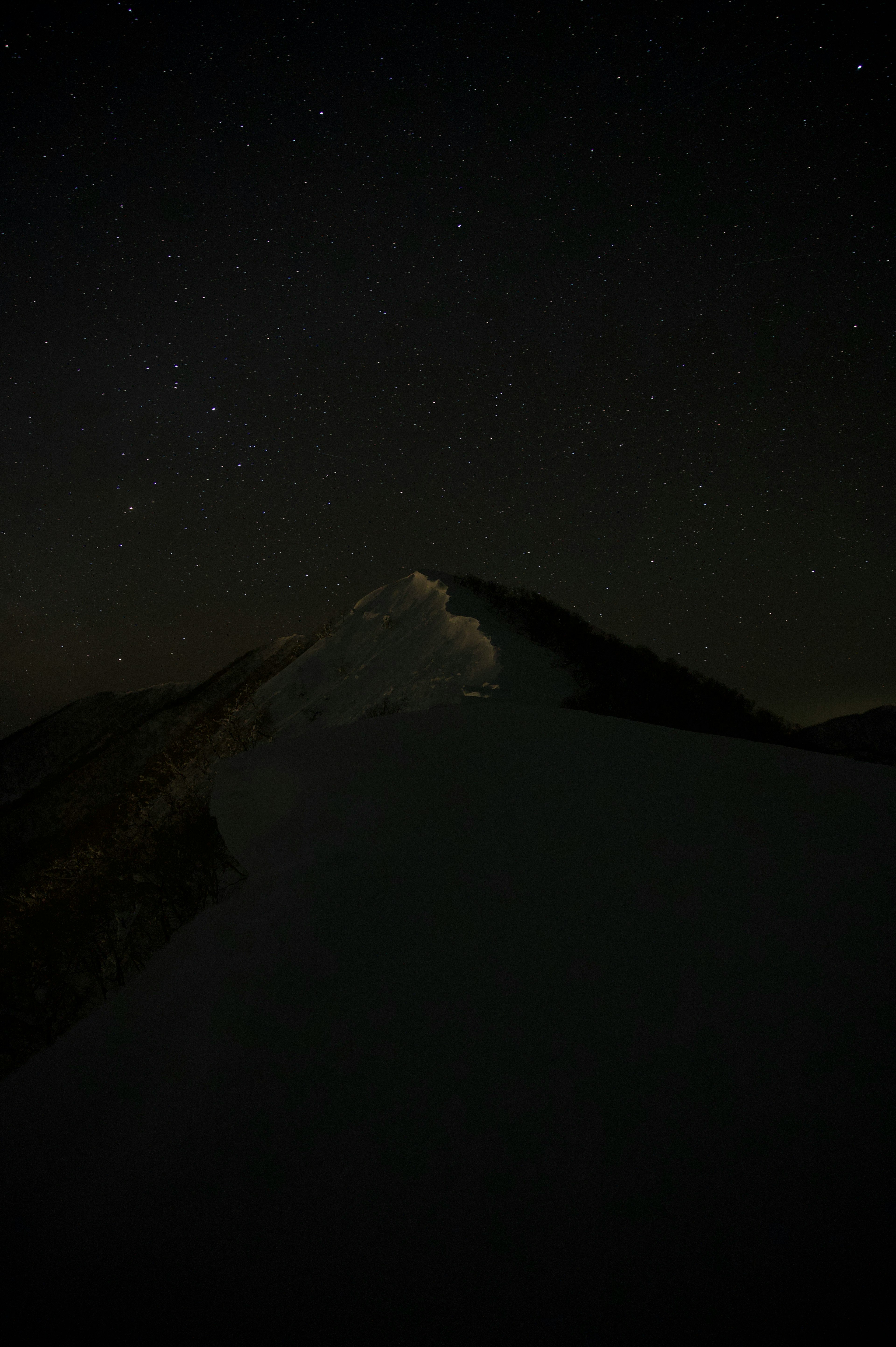 星空の下にそびえる雪山のシルエット