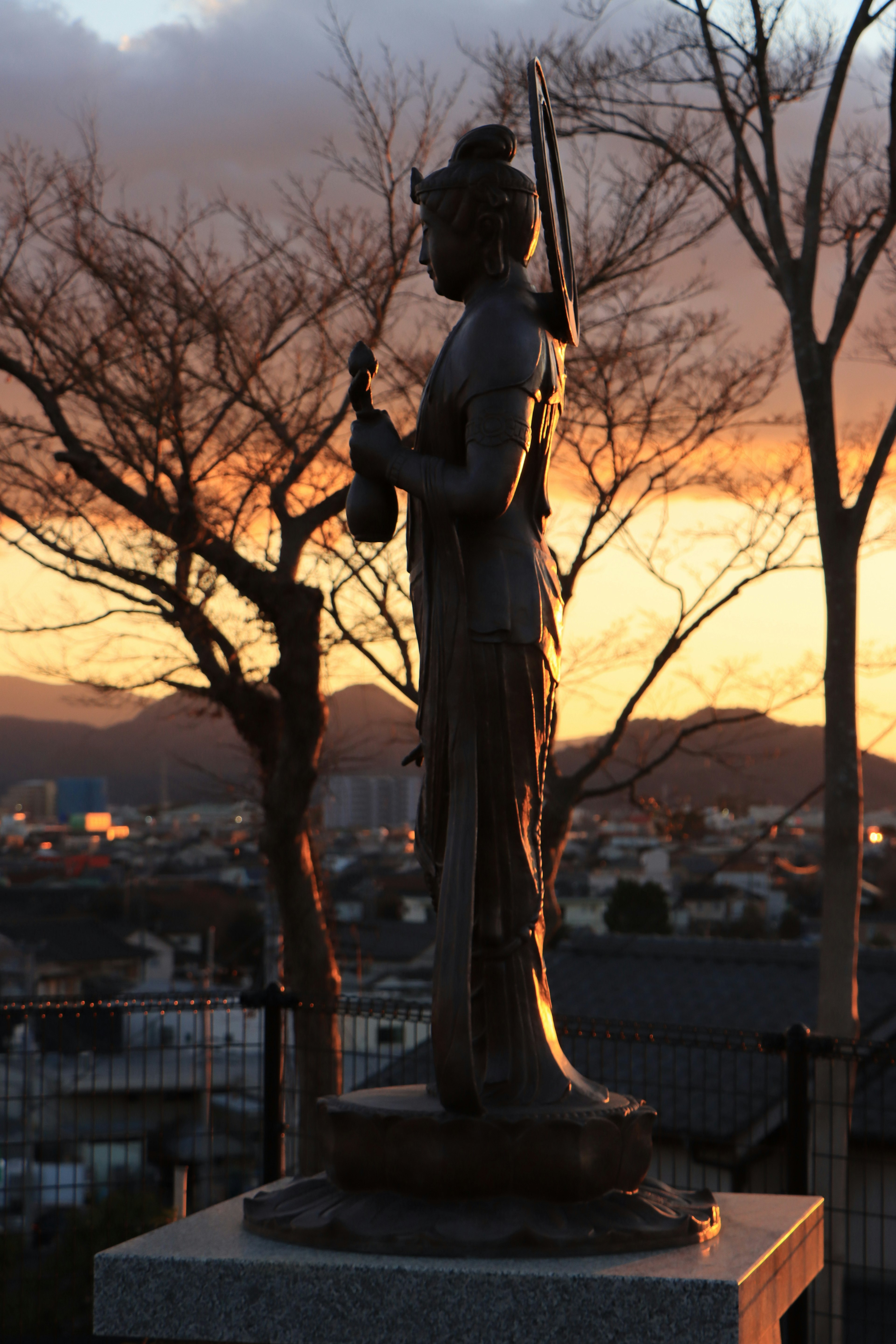 夕日を背に立つ銅像のシルエット