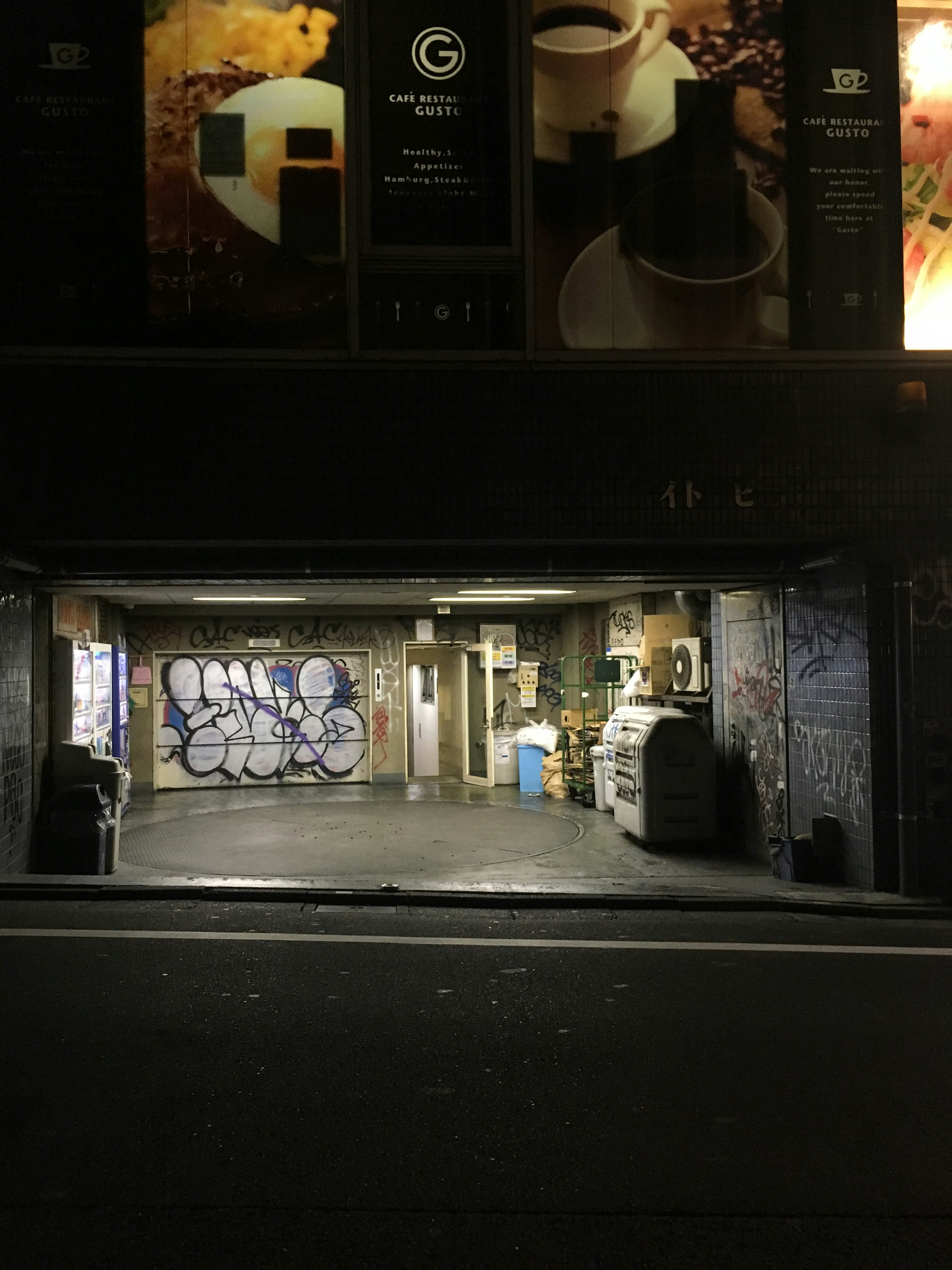 Intérieur d'un garage faiblement éclairé avec graffiti et poubelles