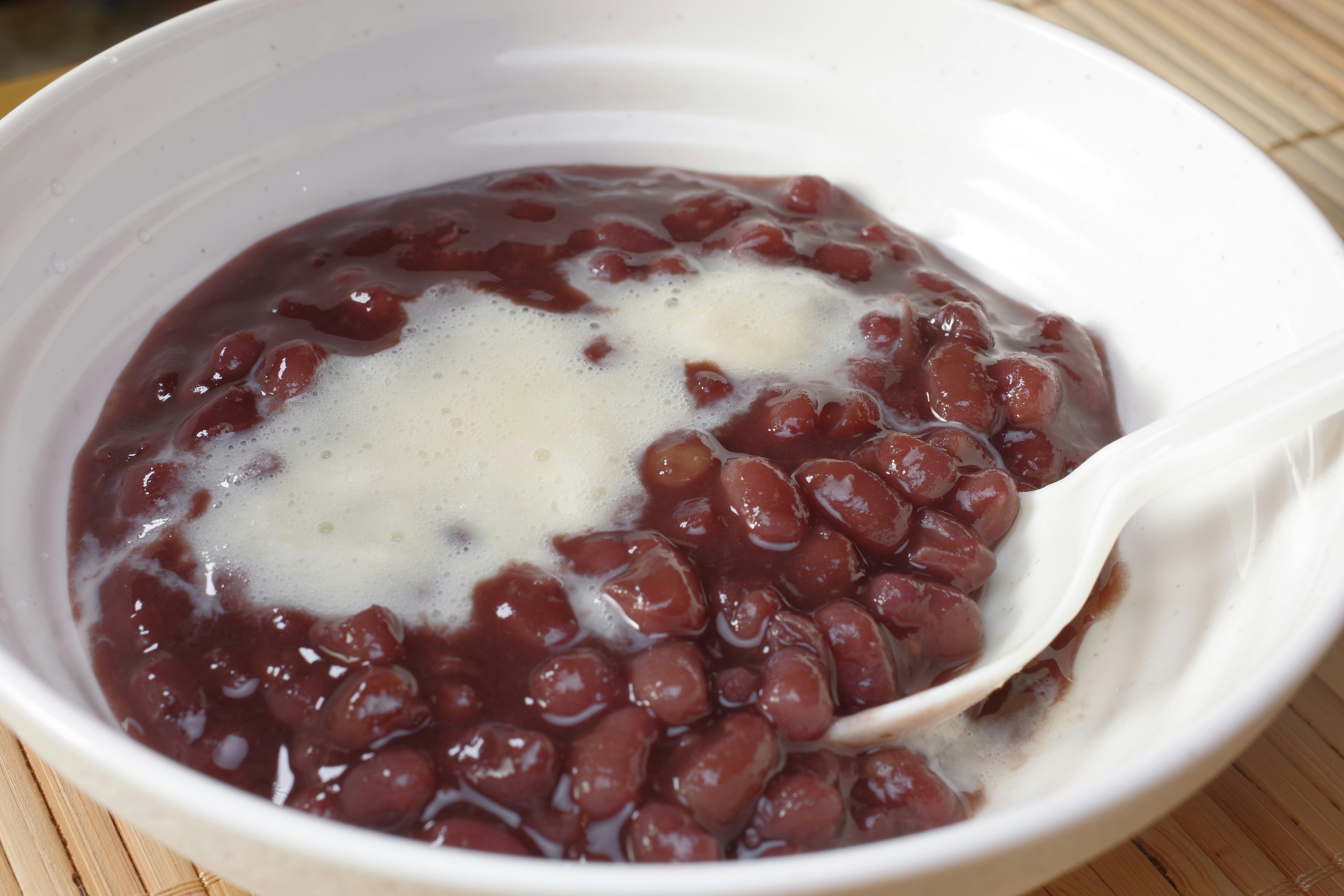 Dessert aux haricots rouges dans un bol blanc avec du lait de coco