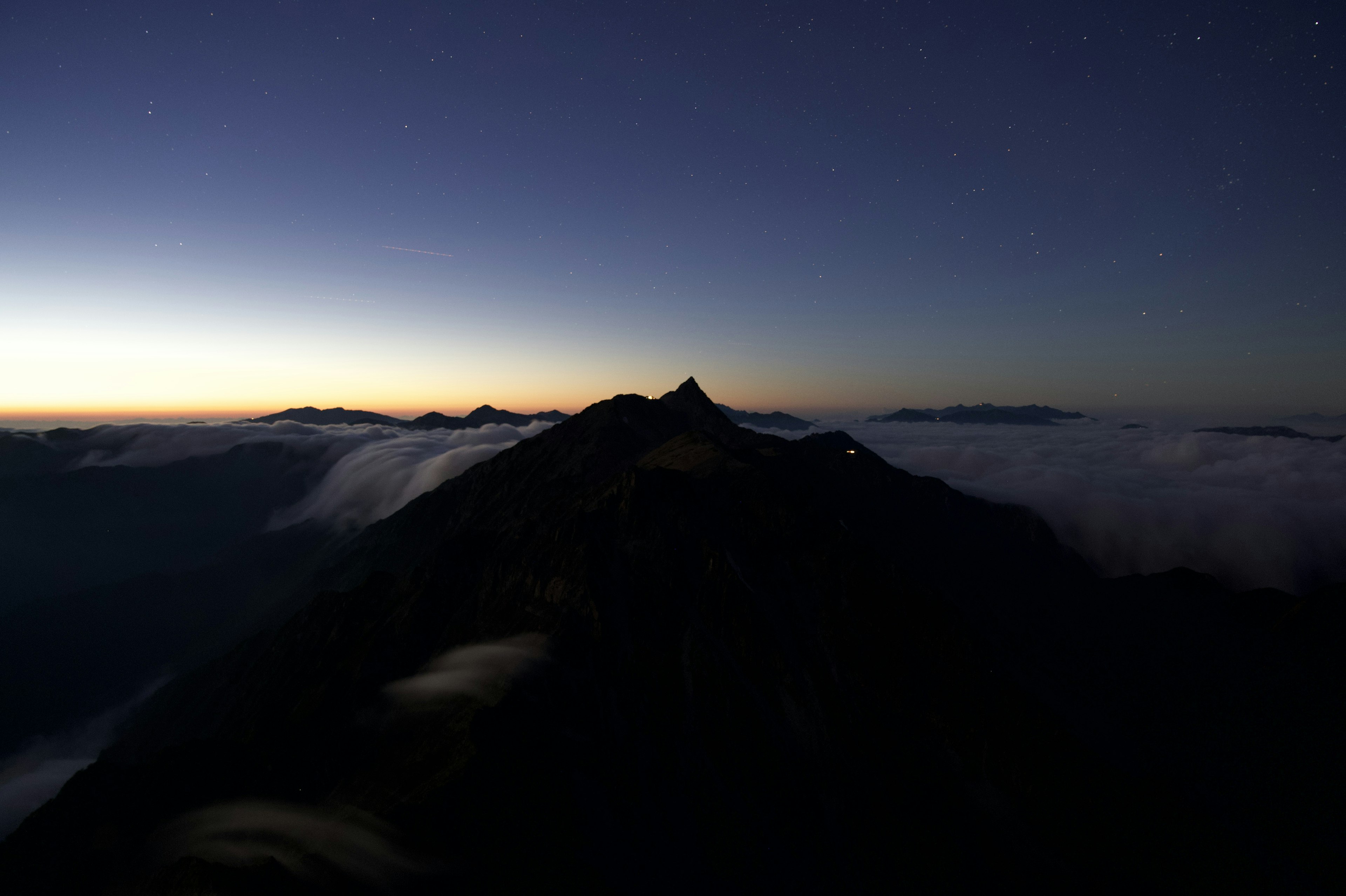 Silhouette de montagnes à l'aube avec des nuages en dessous