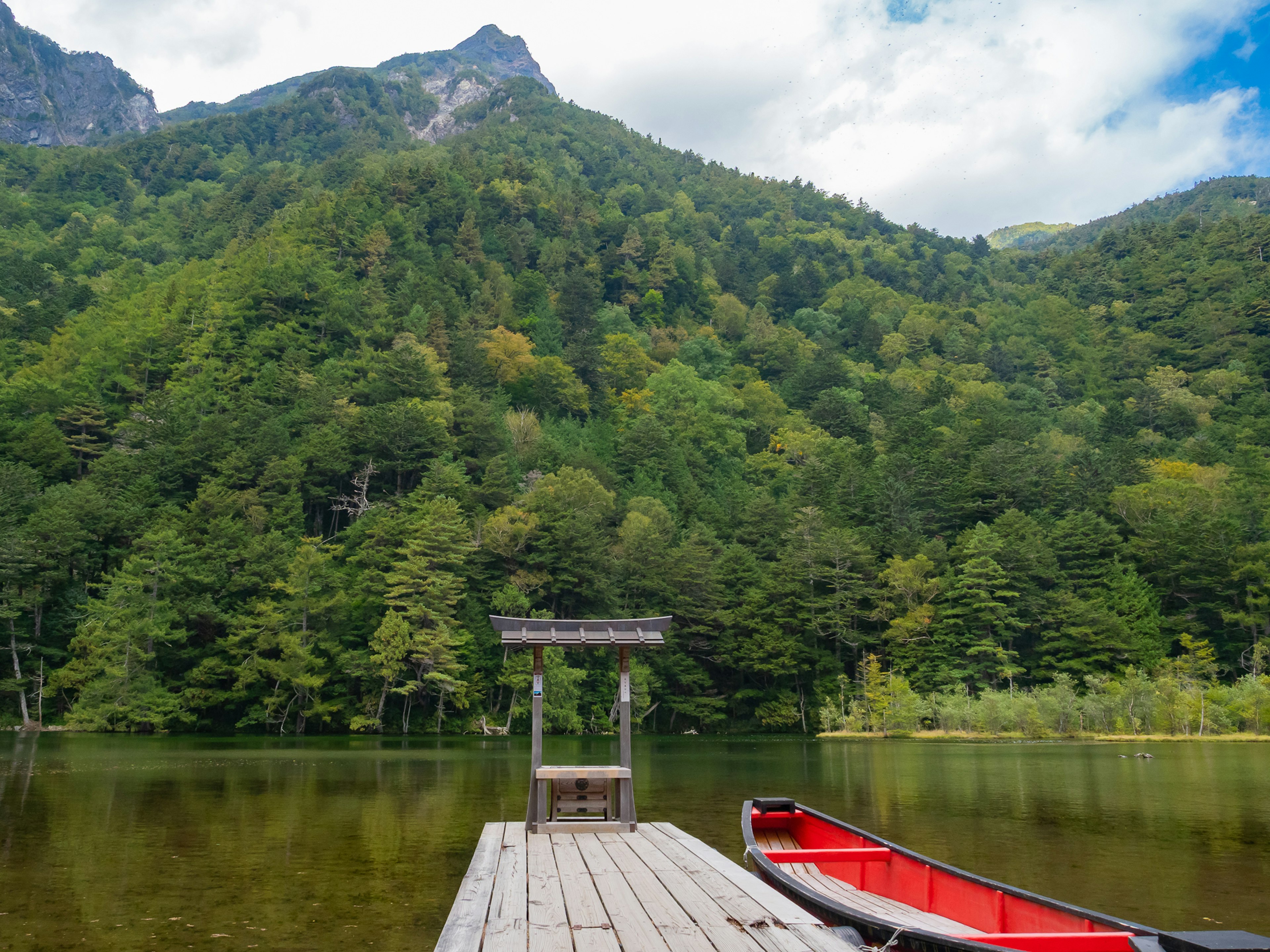 Quai de lac serein entouré de montagnes avec un canoë rouge