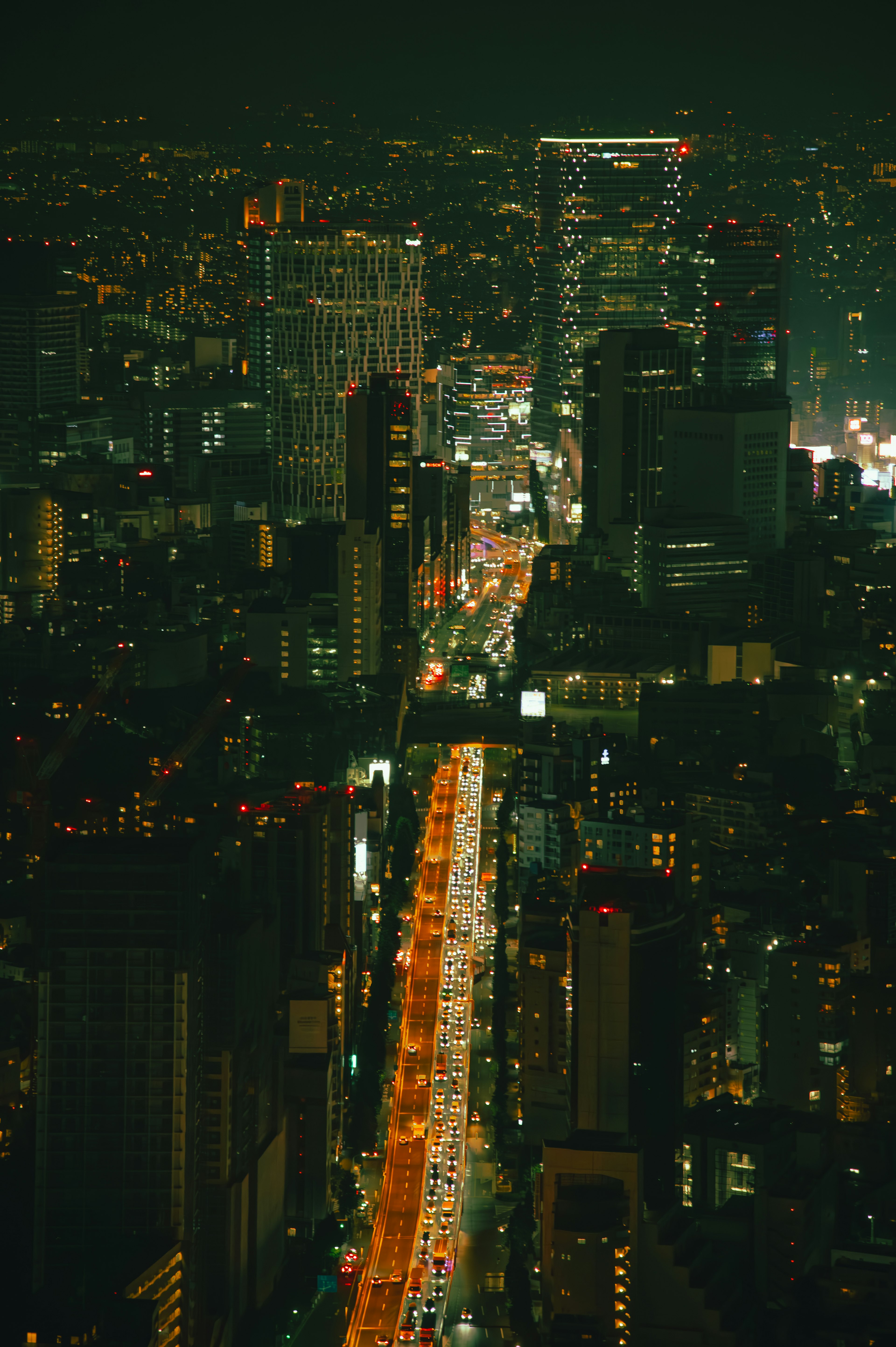 Vista aerea di una città di notte con una strada luminosa al centro circondata da numerosi edifici